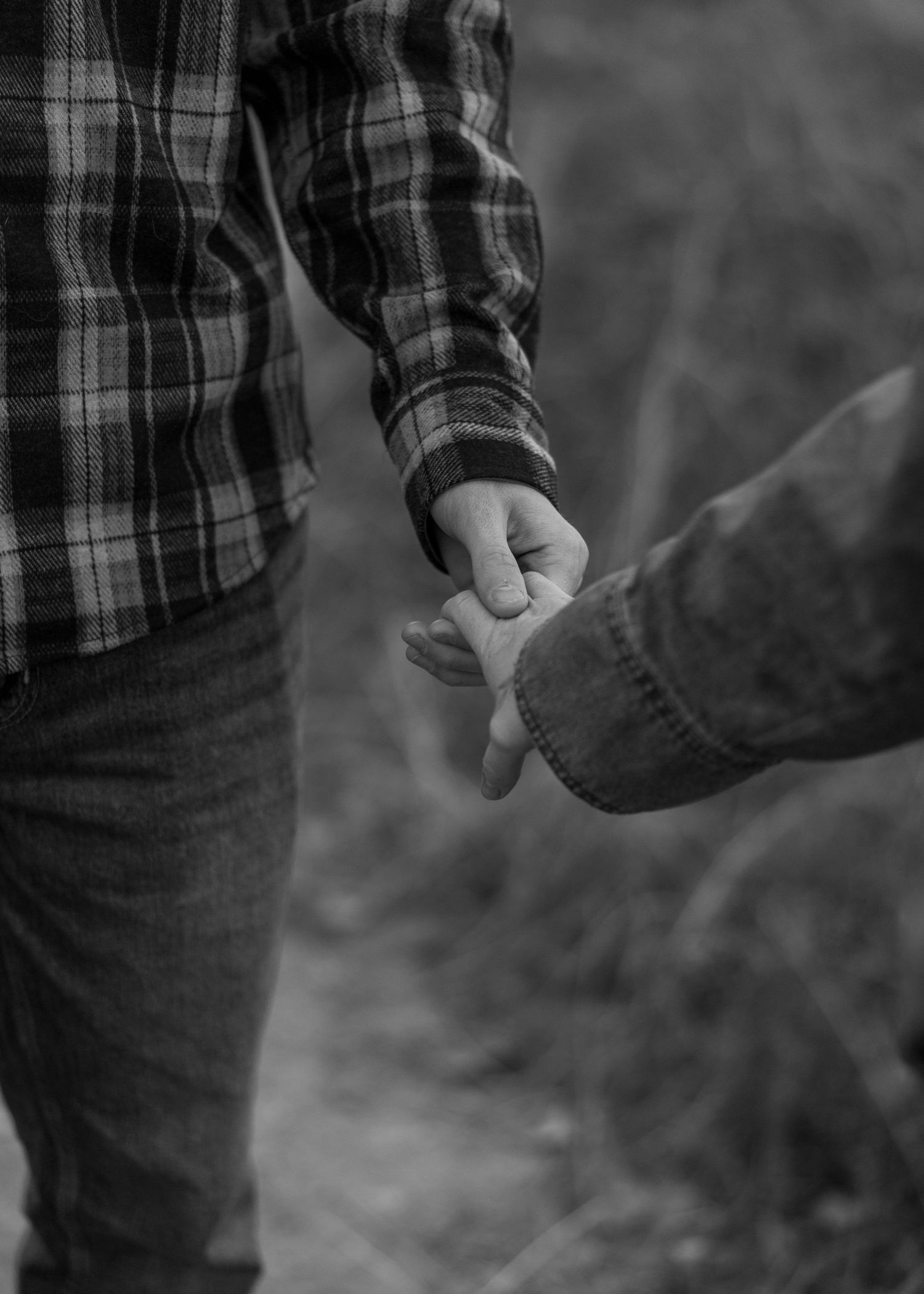 A couple in plaid and denim share a tender moment in a field at sunset.