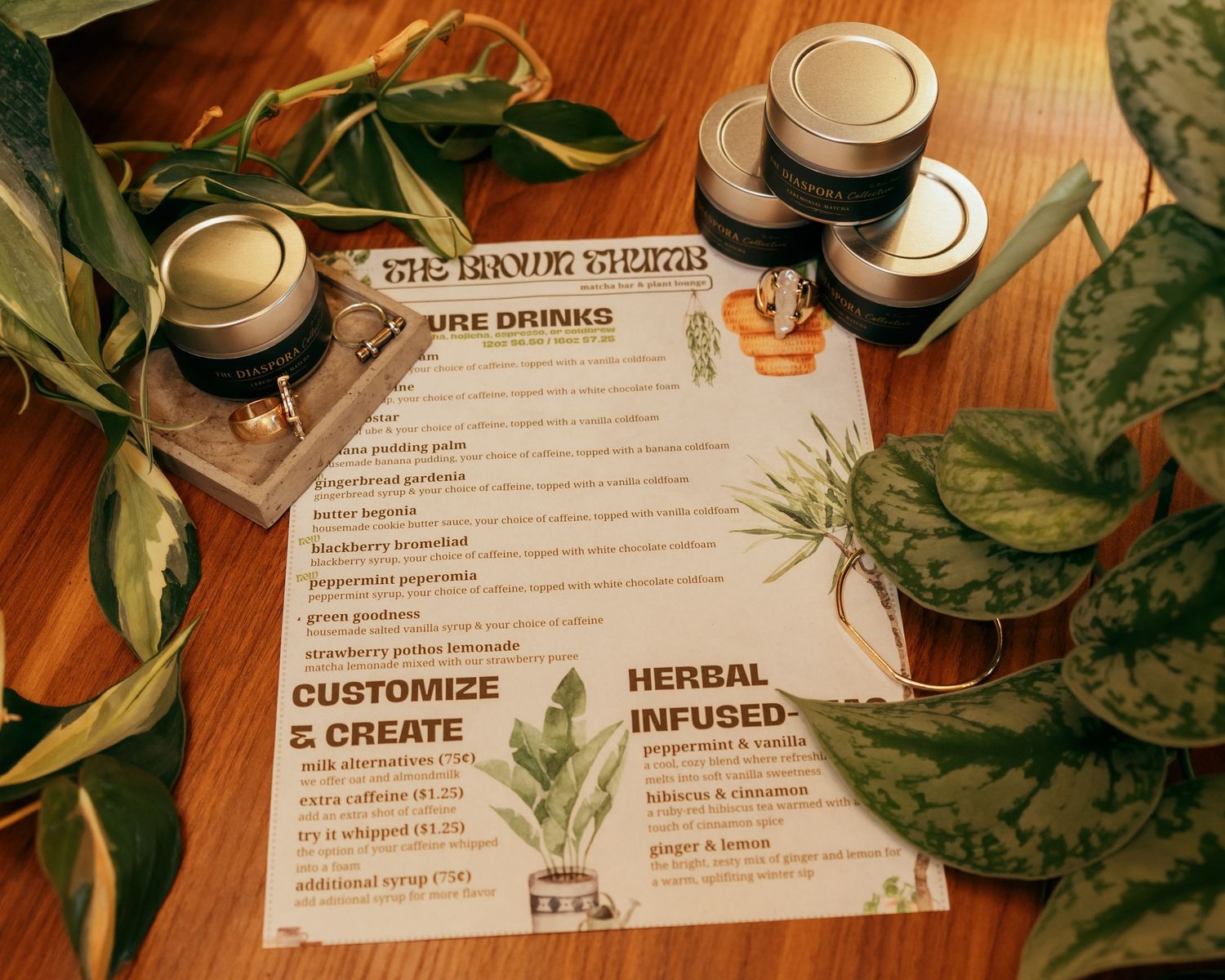 Menu cards and plant decor on wooden table at herbal beverage event.
