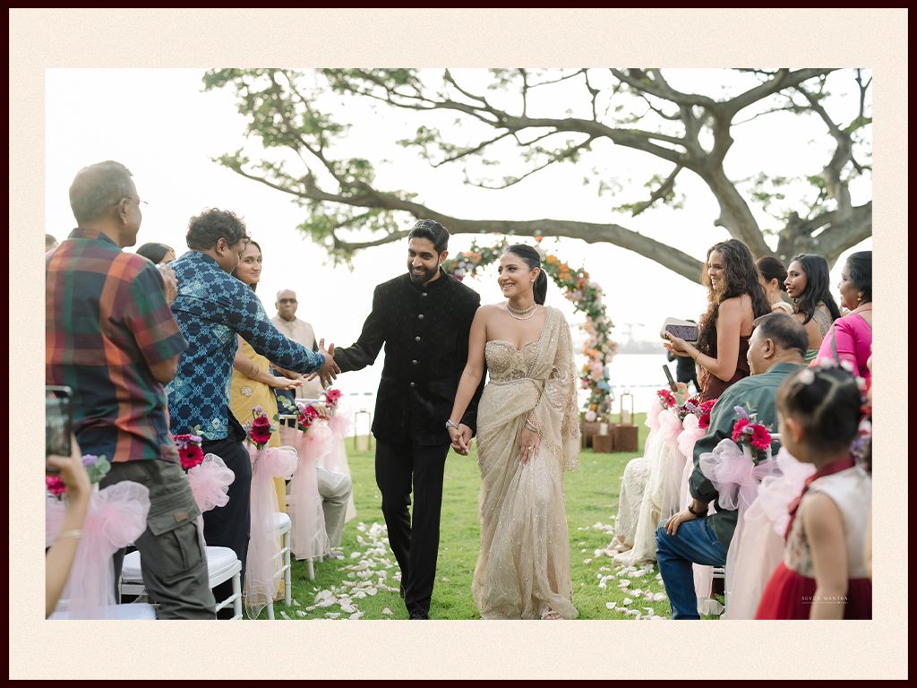 Newlyweds walking back down the aisle after outdoor garden wedding ceremony with cheering guests.