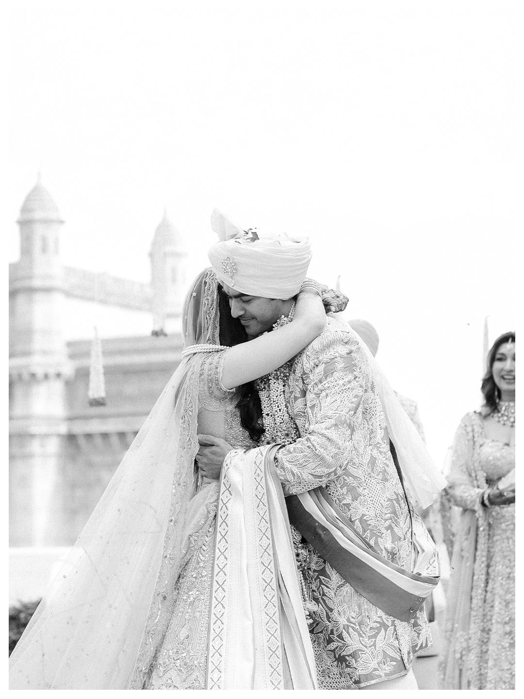 Black and white photo of Indian bride and groom embracing warmly after their wedding ceremony.