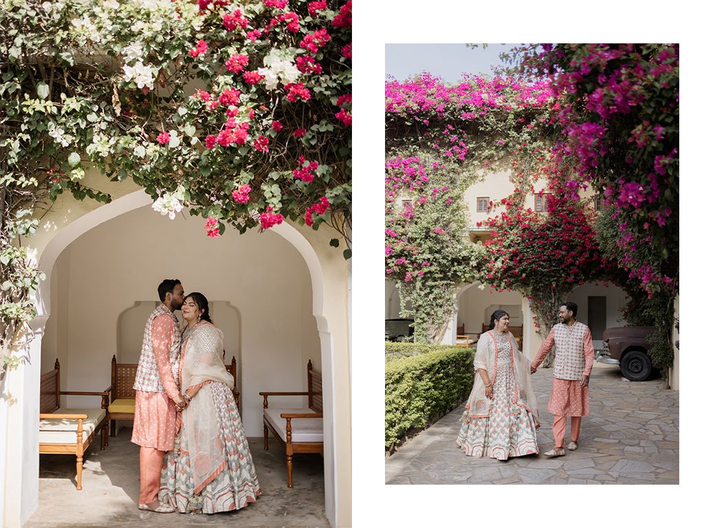 Indian wedding couple in peach lehenga and sherwani embrace under blooming pink bougainvillea arch.
