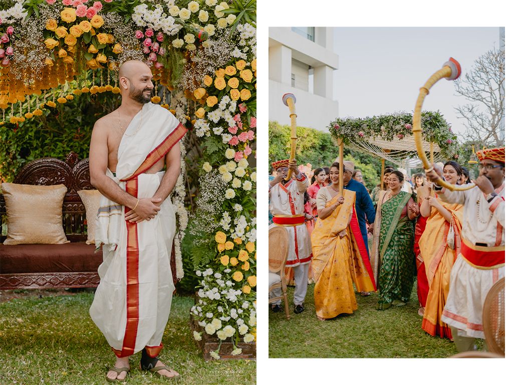 Groom in white dhoti stands at floral mandap as bride arrives with family in vibrant traditional Indian attire.