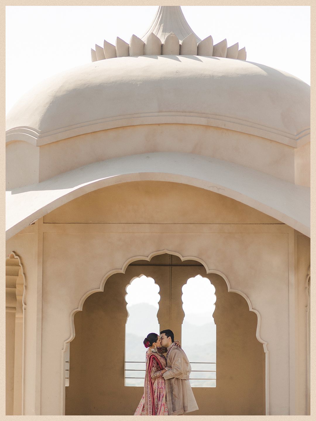Indian wedding couple shares intimate moment under ornate white arch at Fairmont Jaipur.