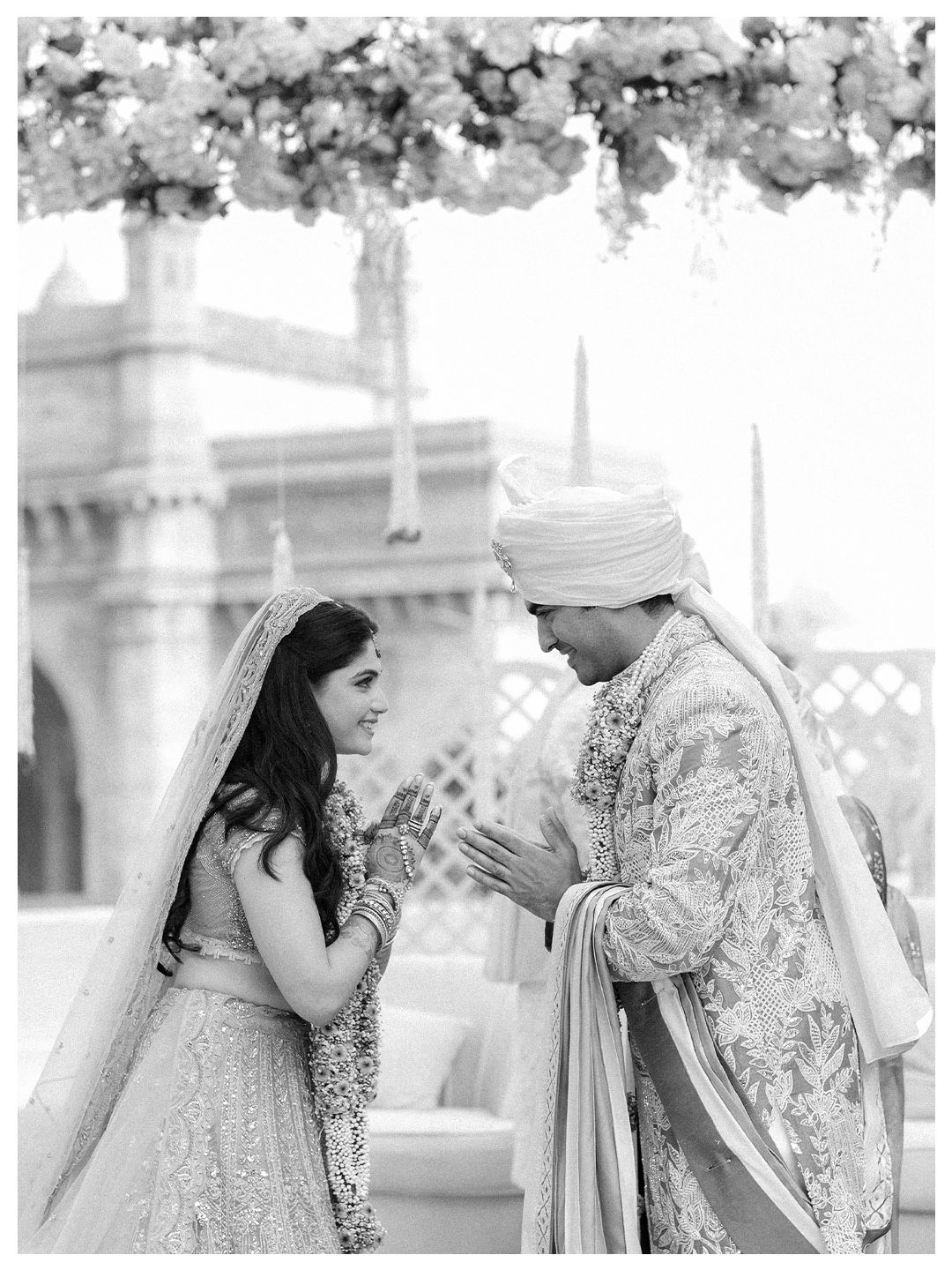 Black and white photo of Indian bride and groom sharing intimate moment at wedding mandap.