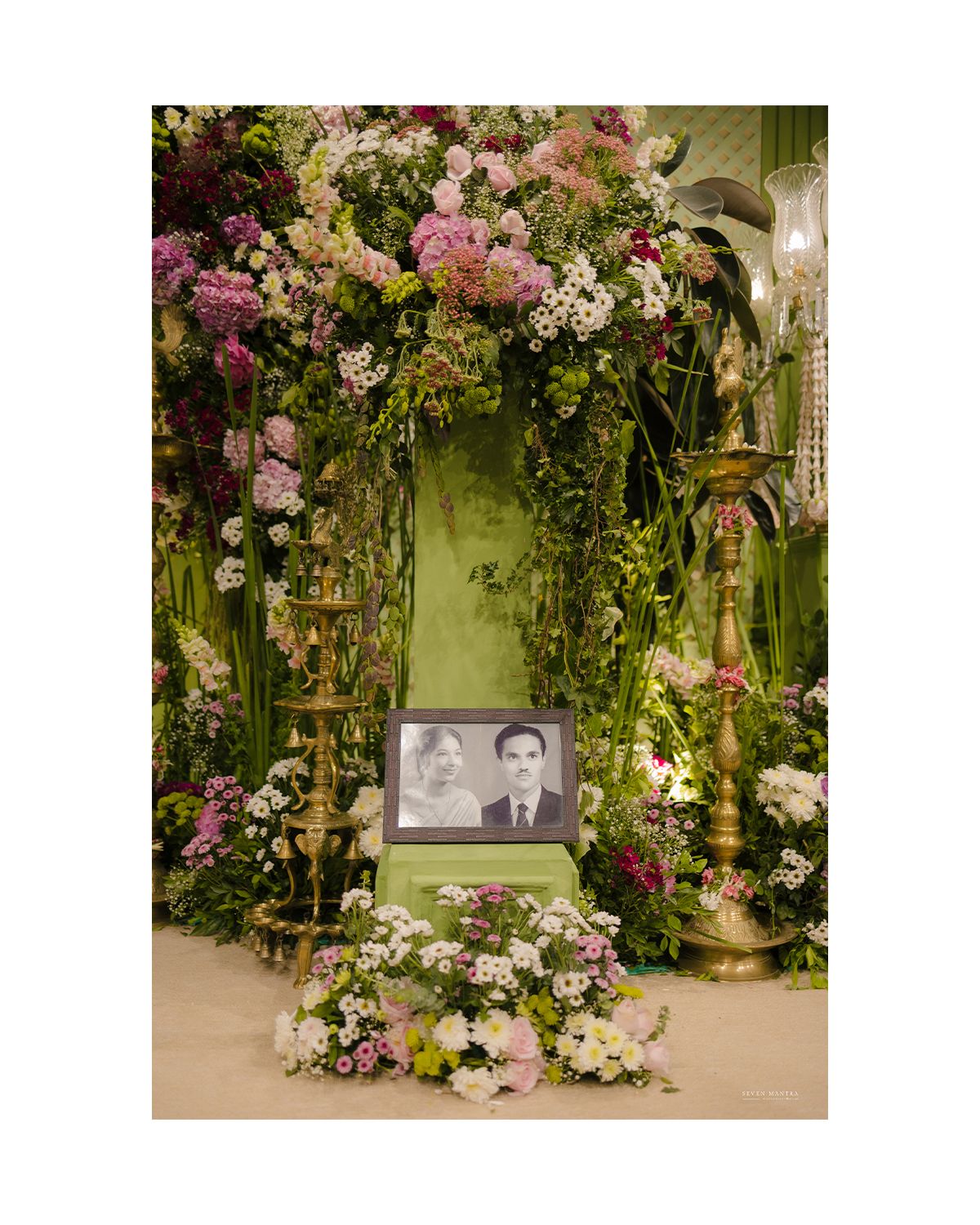 Lush floral wedding altar with pink and white blooms surrounding a vintage black and white couple photo.