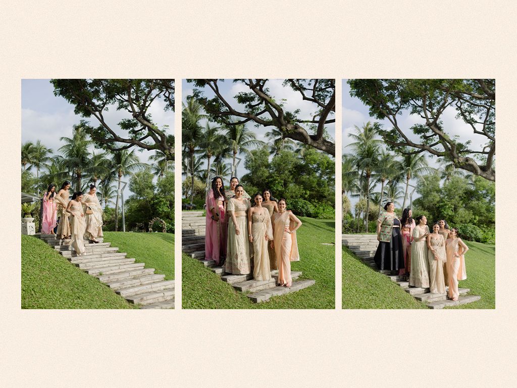 Bridesmaids in neutral toned gowns posing on garden steps under a large tropical tree.