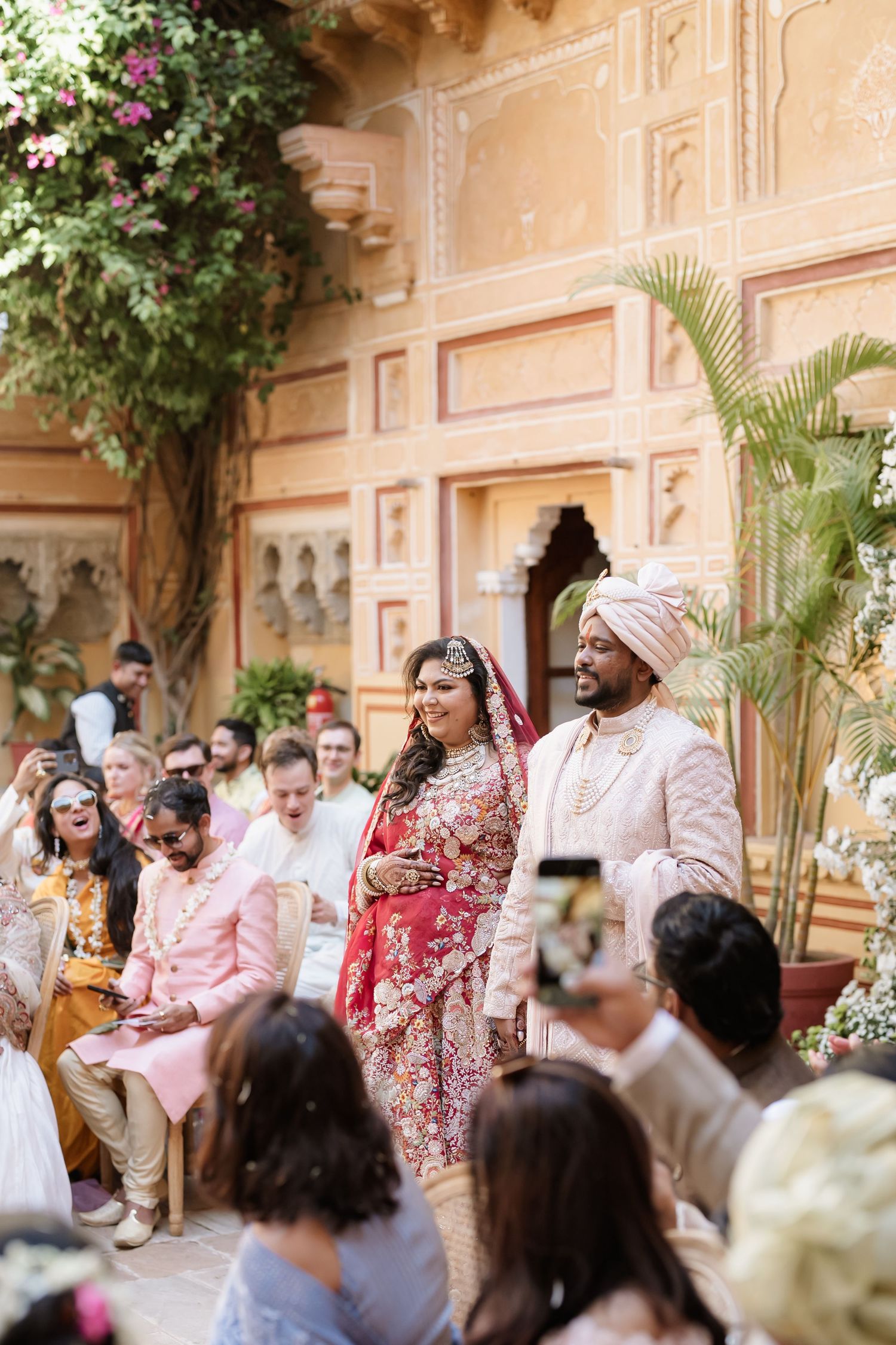 Indian bride and groom walking down the aisle at a traditional wedding ceremony in a royal palace.
