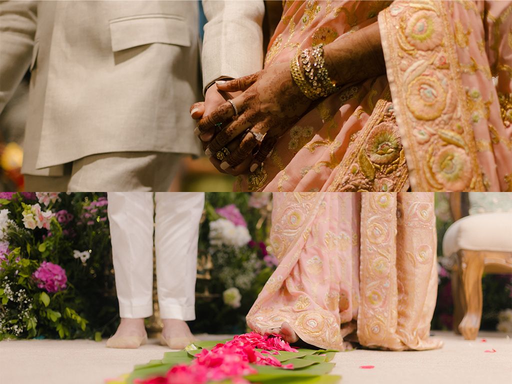 Close-up of Indian bride and groom holding hands during traditional Hindu wedding ceremony with floral decorations.