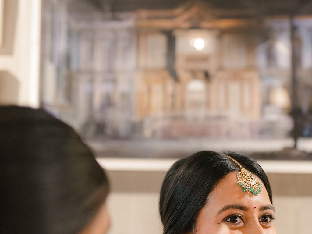 Beautiful Indian bride wearing maang tikka jewelry with bindi during wedding preparation.