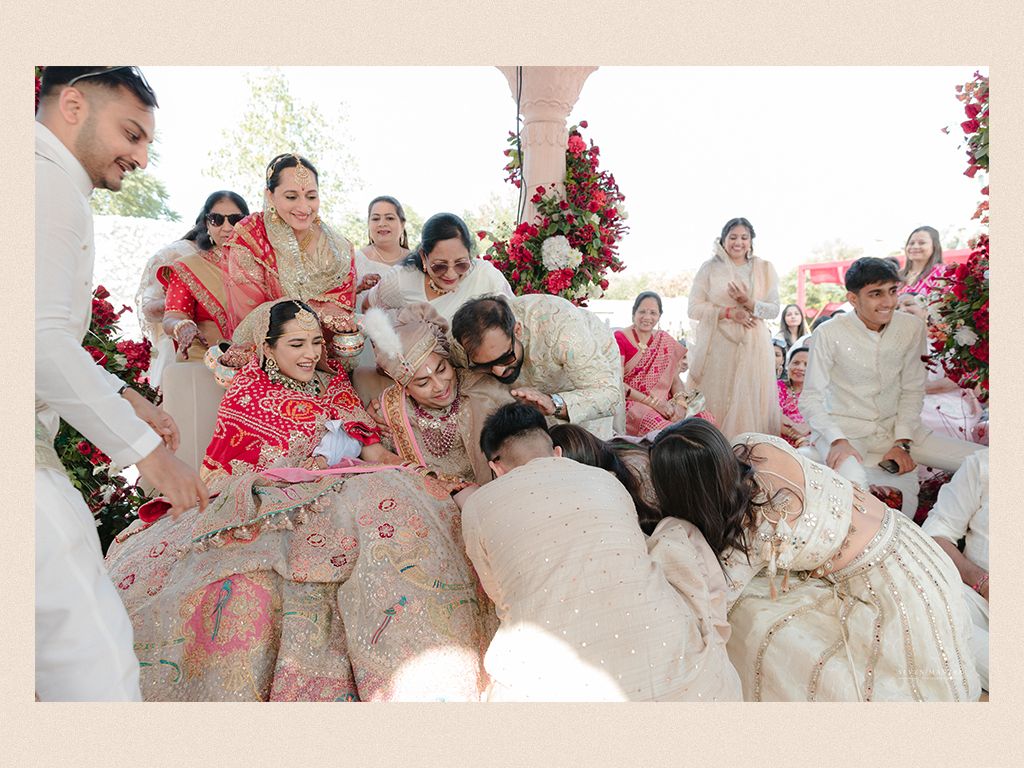 Indian wedding ceremony with bride in red lehenga surrounded by family during traditional ritual celebration.