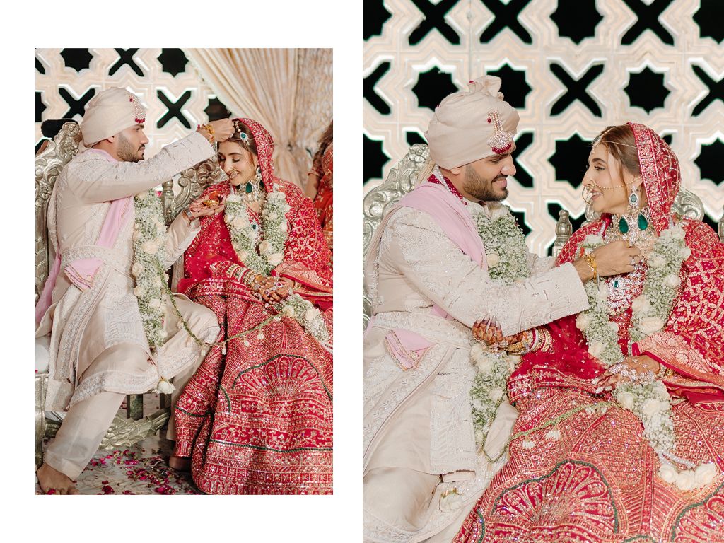 Indian bride and groom smiling joyfully during jaimala garland exchange ceremony at traditional wedding.