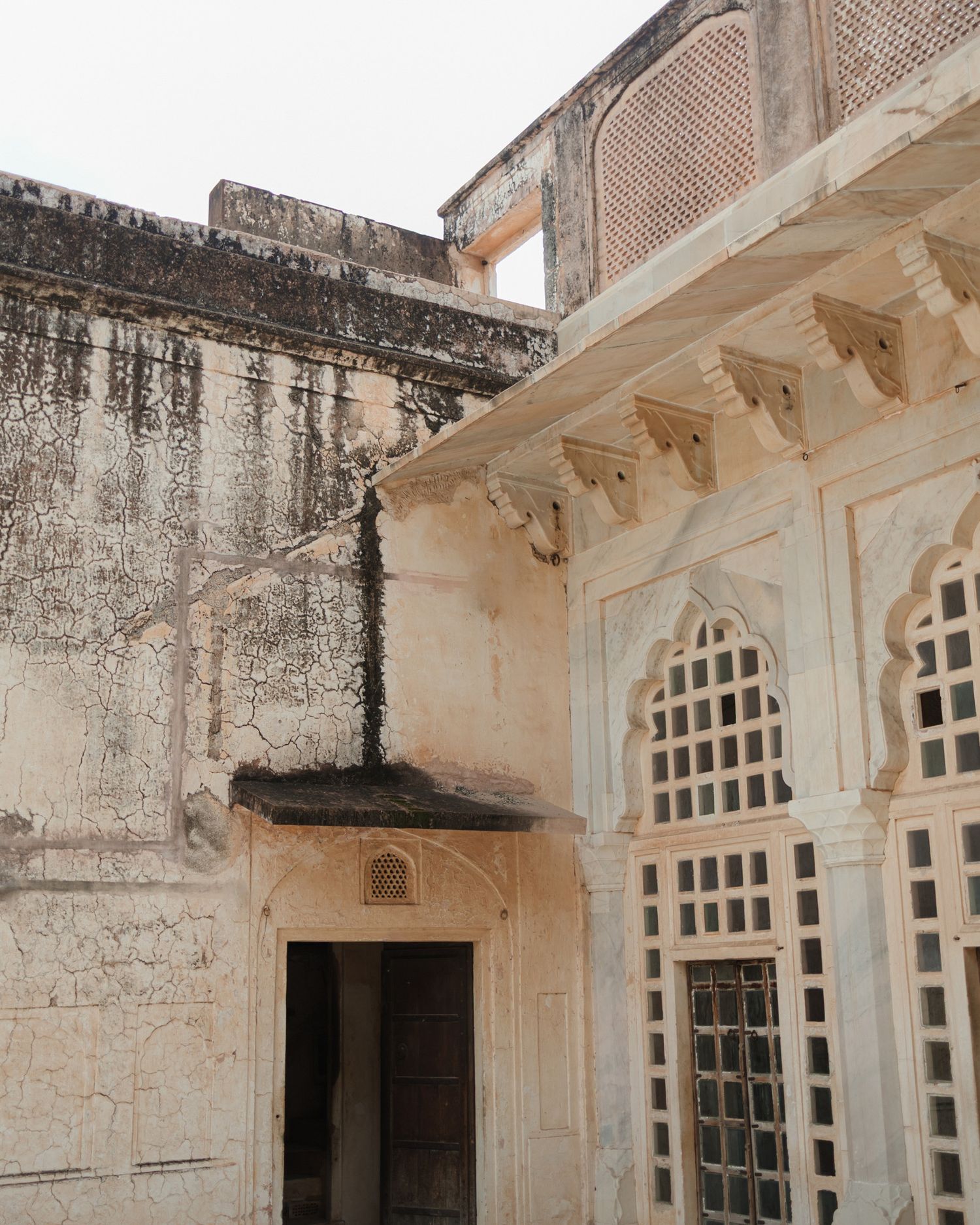 Ancient Rajasthani palace architecture featuring ornate white marble lattice windows and weathered stone walls in India.