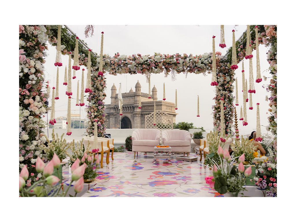 Floral mandap with pink and white flowers framing the iconic Gateway of India at Mumbai wedding.