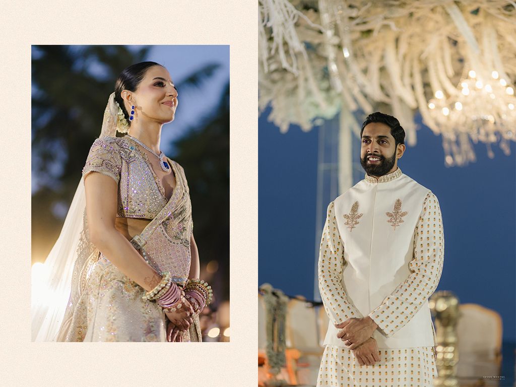 Indian bride in ivory lehenga and groom in white sherwani portrait at elegant beach wedding ceremony.
