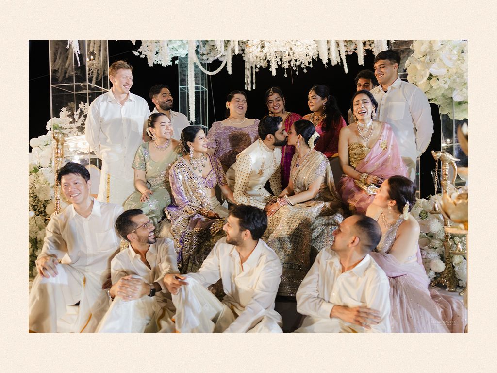 Wedding guests laughing and celebrating together under elegant white floral chandelier installation.