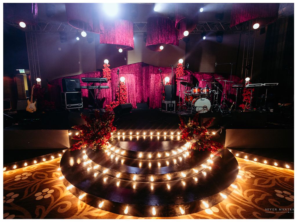 Elegant wedding stage decorated with candles and pink floral backdrop with concert lighting setup.