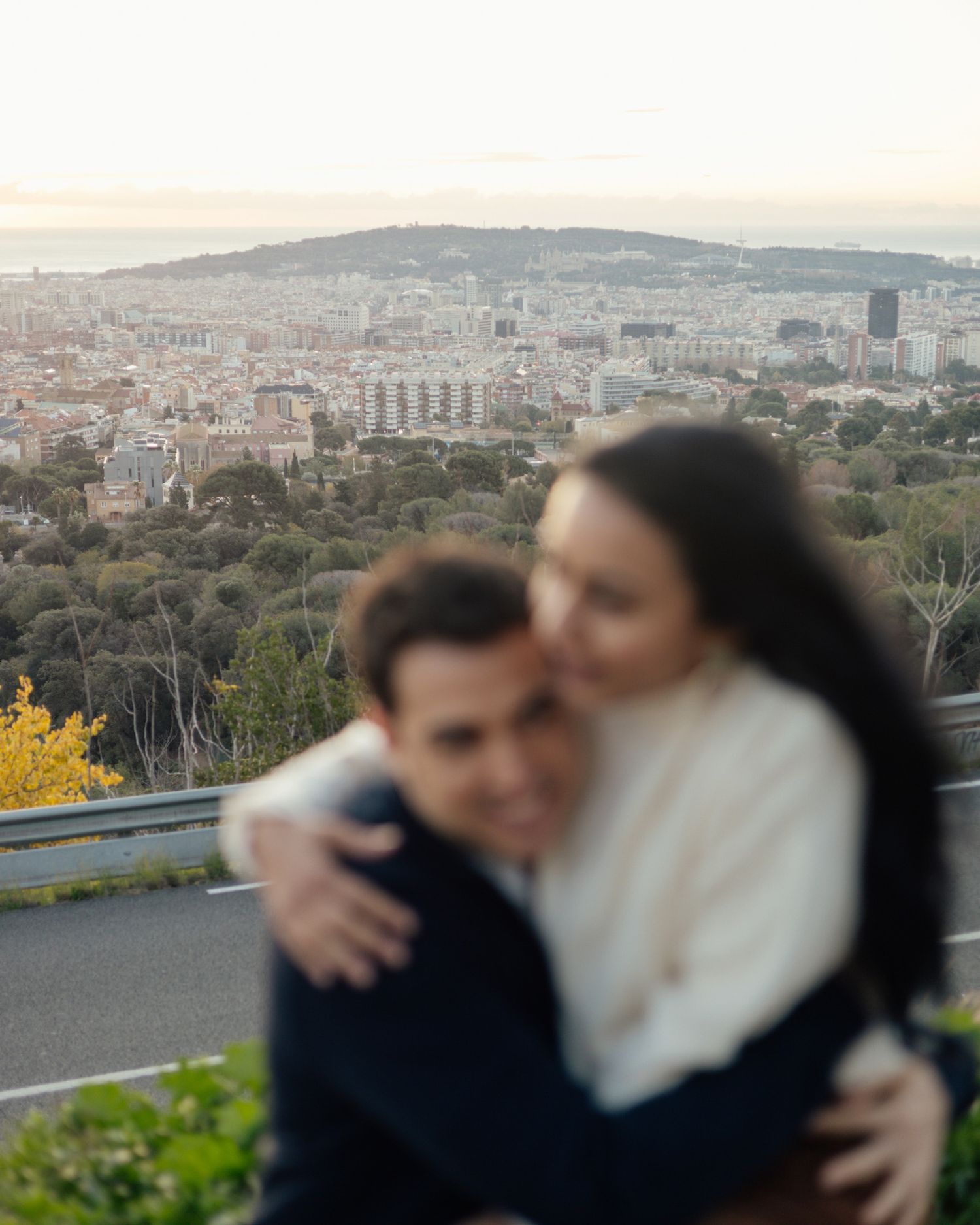 Couple embracing with panoramic city skyline view at sunset in Barcelona.