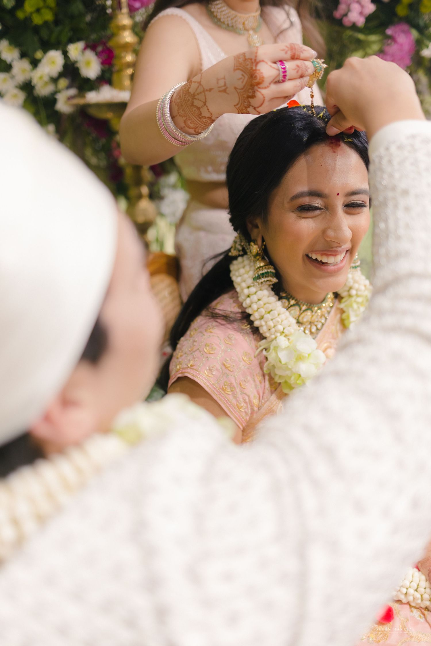 Joyful Indian bride laughing during traditional wedding garland exchange ceremony.