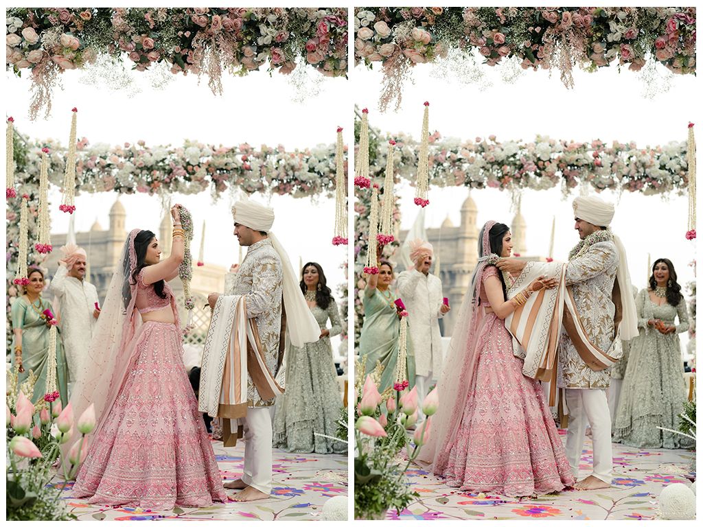 Indian bride and groom exchanging garlands under a floral mandap during their wedding ceremony.