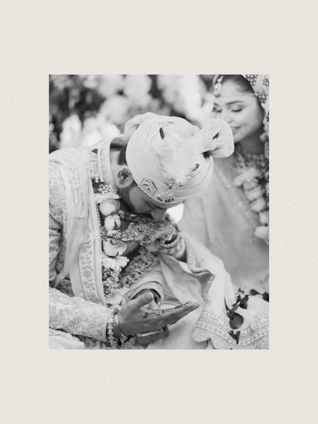 Black and white photo of groom bowing during traditional Indian wedding phera ceremony.