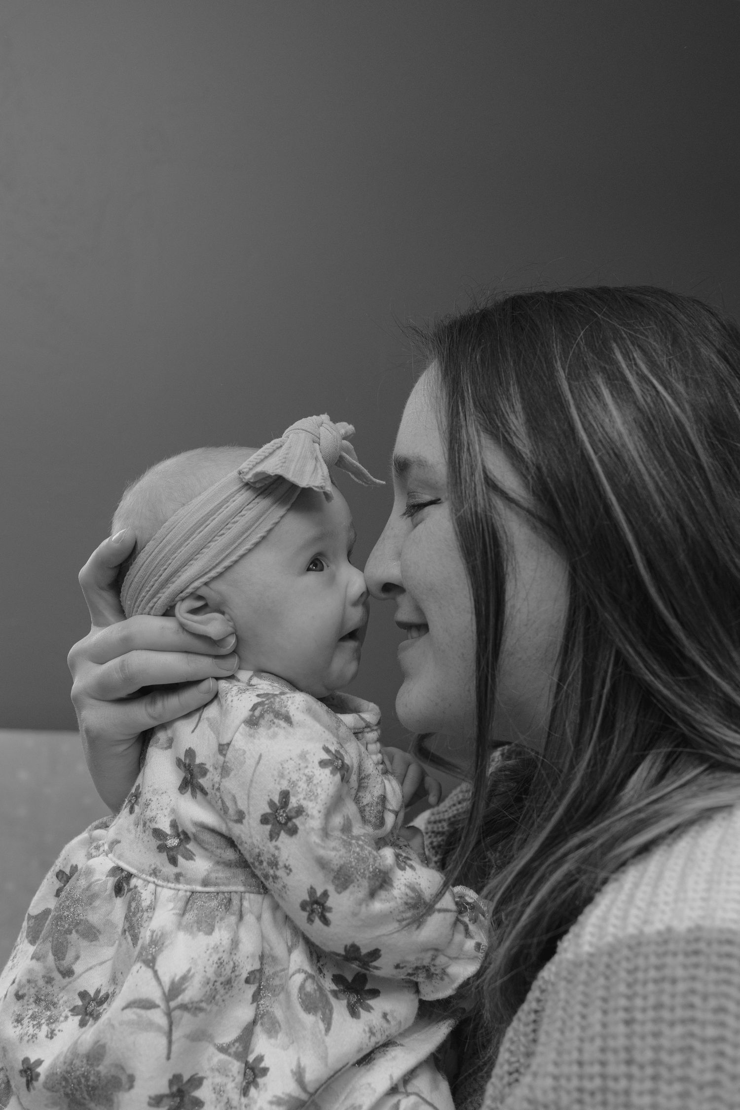 Black and white portrait of a mother tenderly holding her newborn baby face to face.