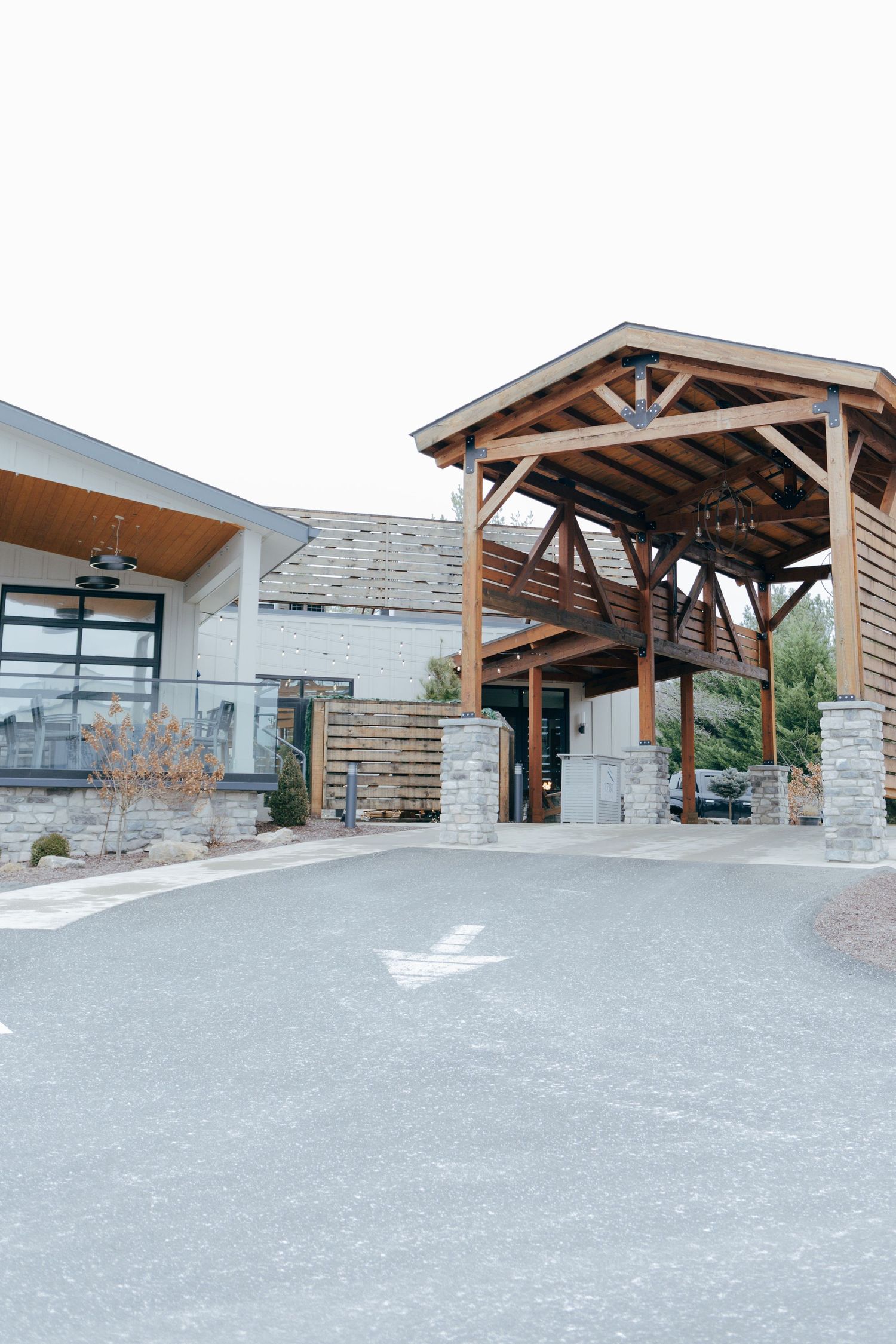 The exterior of a modern building features a wooden timber-frame covered entrance with stone pillars.