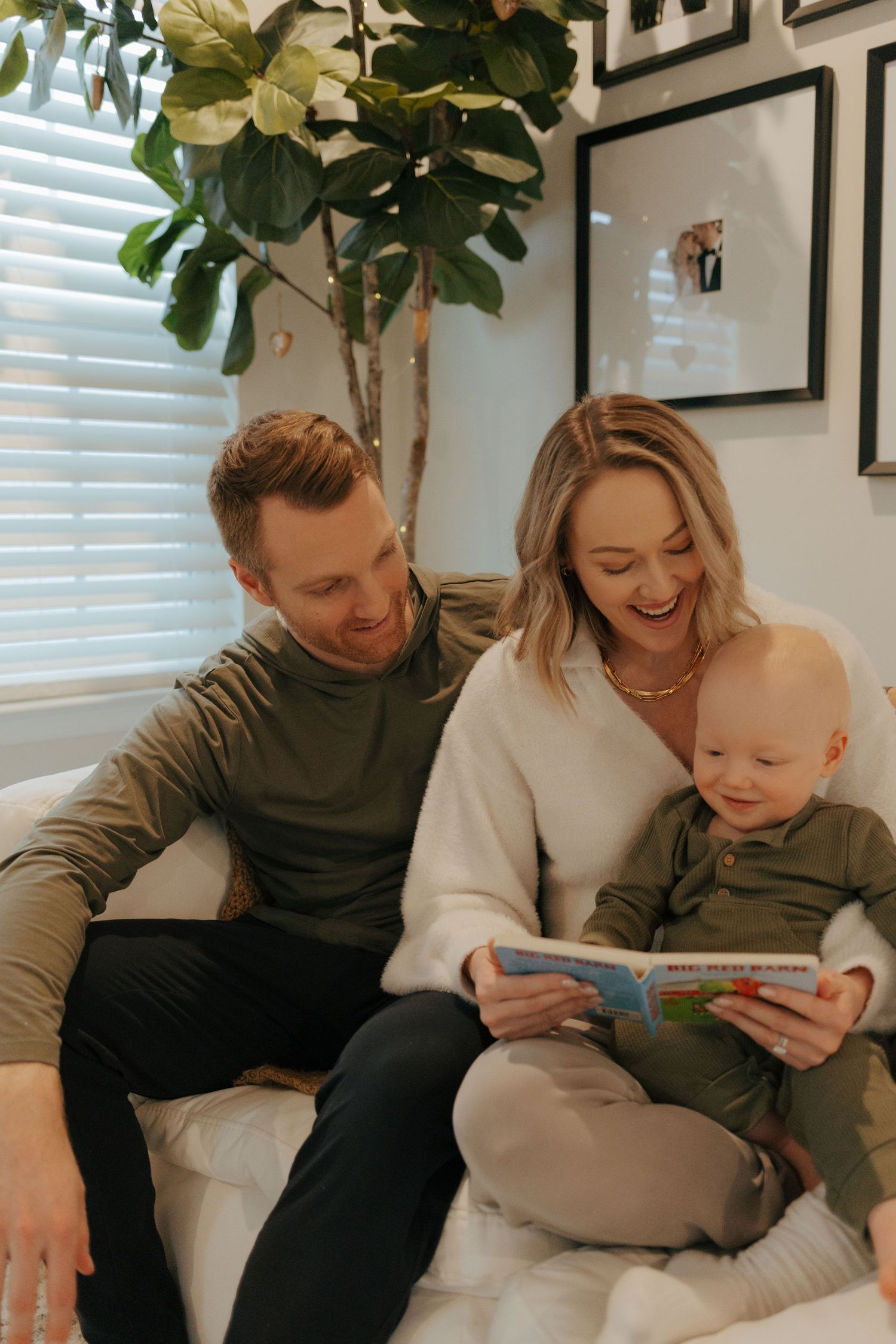 A happy family reads a colorful book together, laughing in a bright, stylish living room.