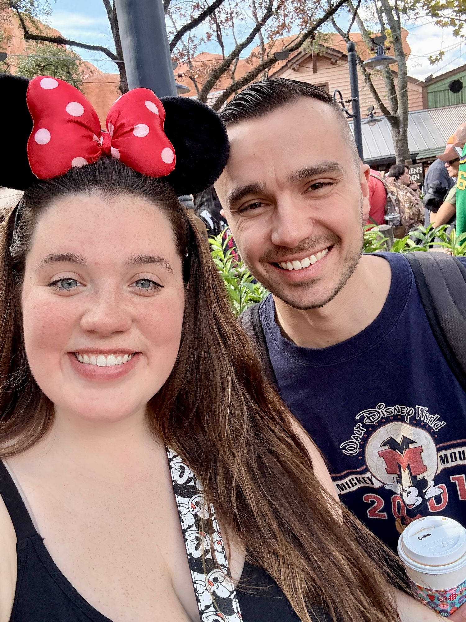Smiling couple taking a selfie at Walt Disney World theme park together.
