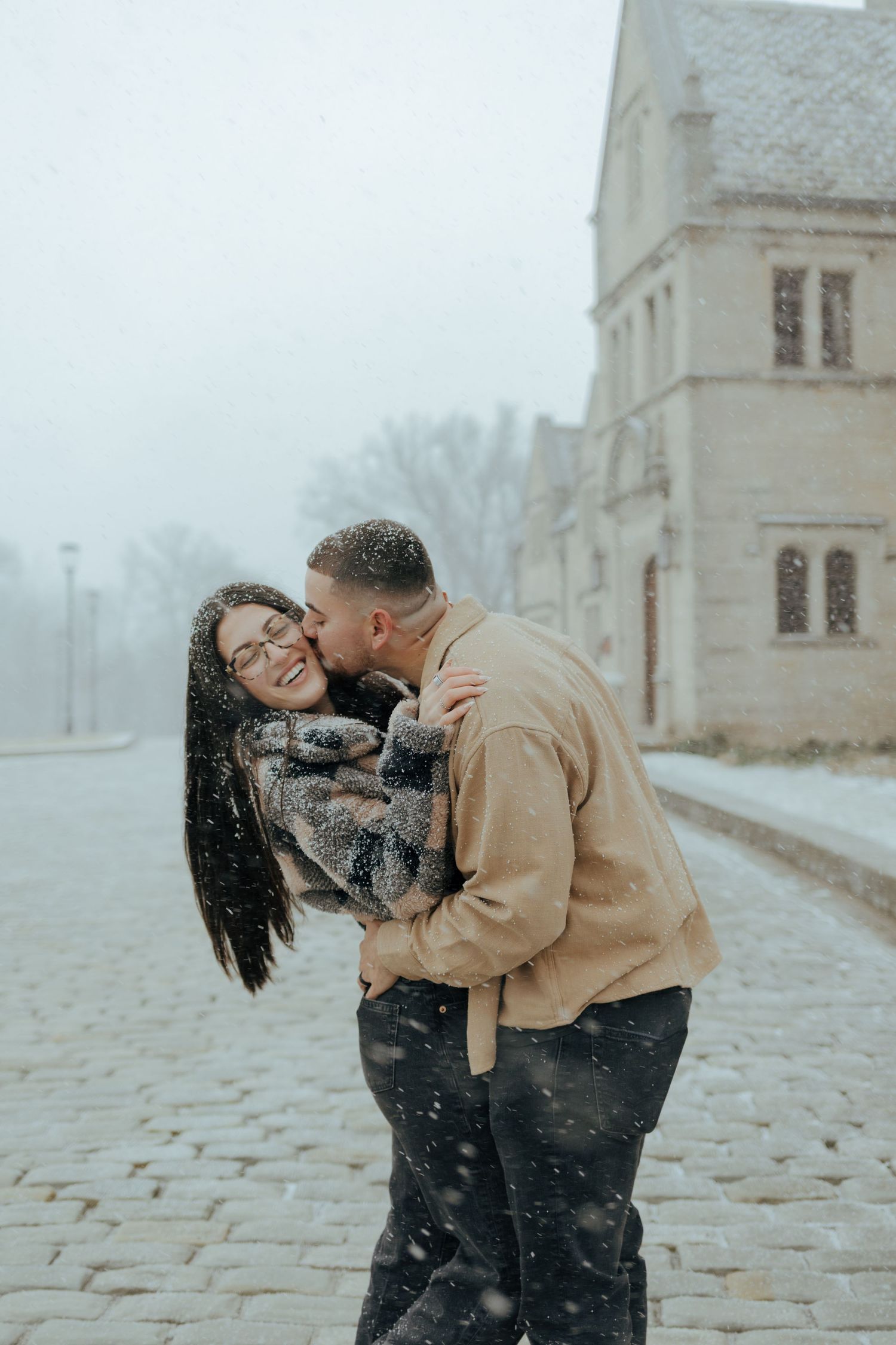 Couple embracing and kissing in the snow at Hartwood Acres in Pittsburgh