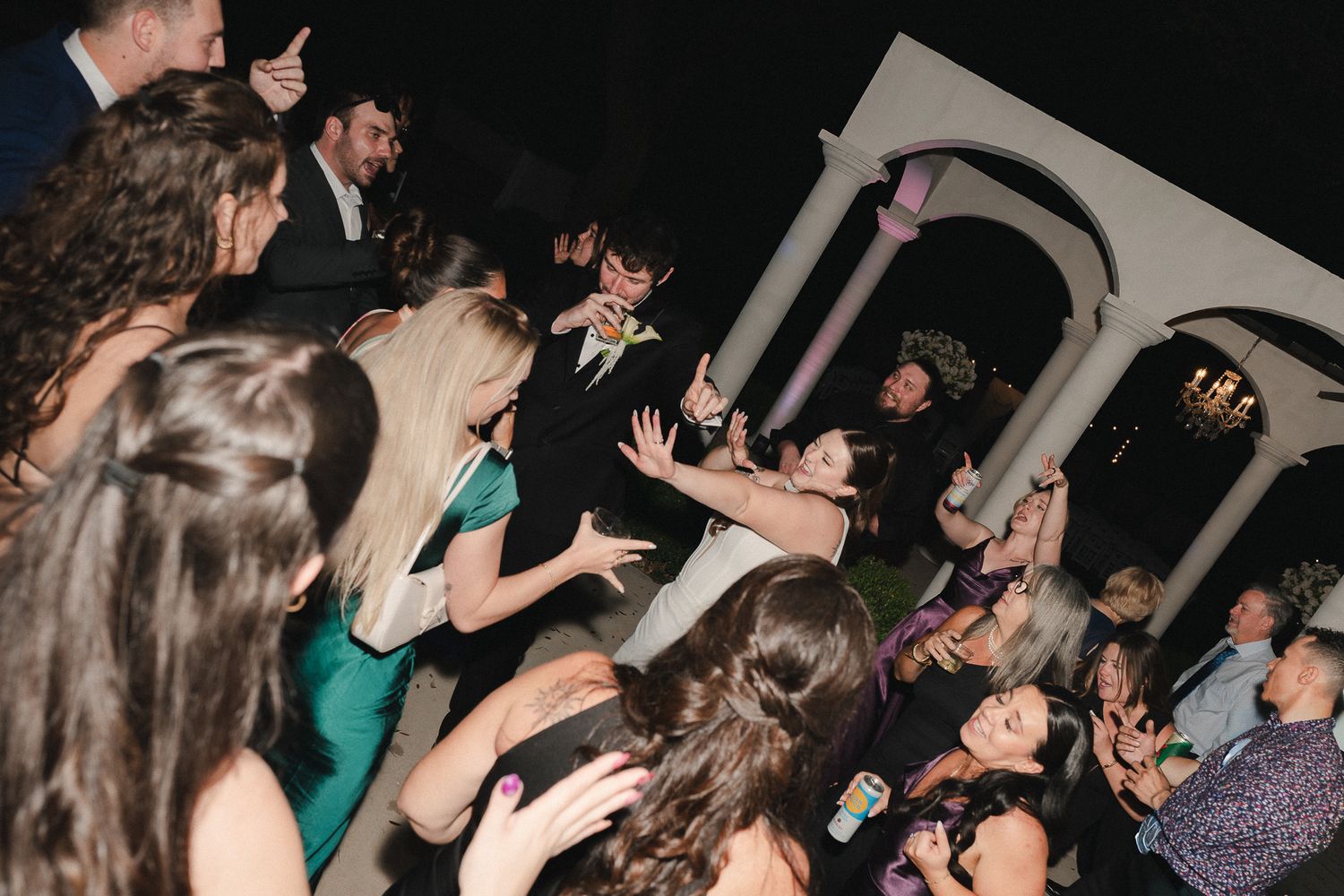 Guests dancing and celebrating at a formal wedding reception party in an elegant venue at night.