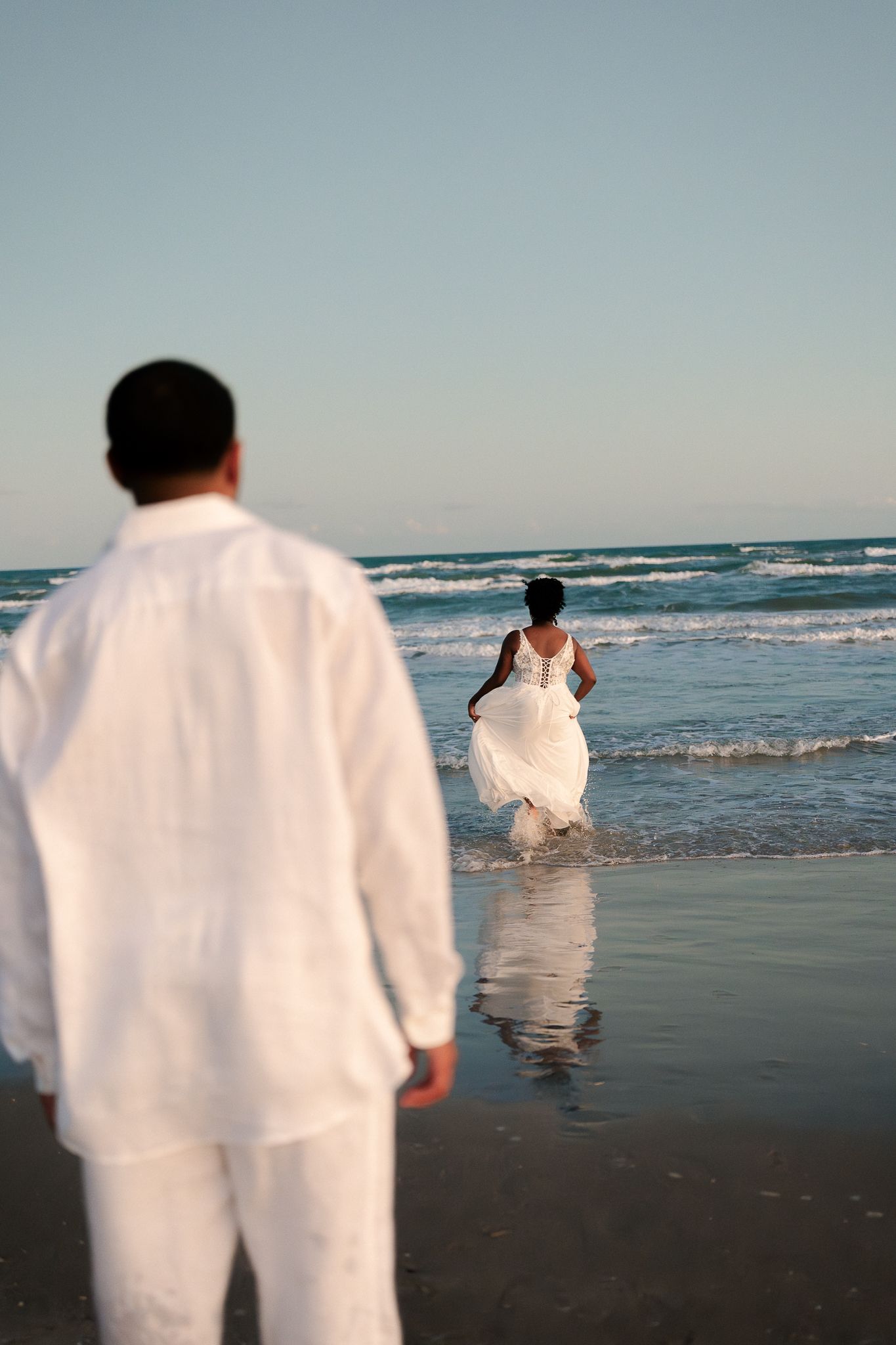 A sequence of images showing people in white clothing walking along a beach shoreline with ocean waves in the background.