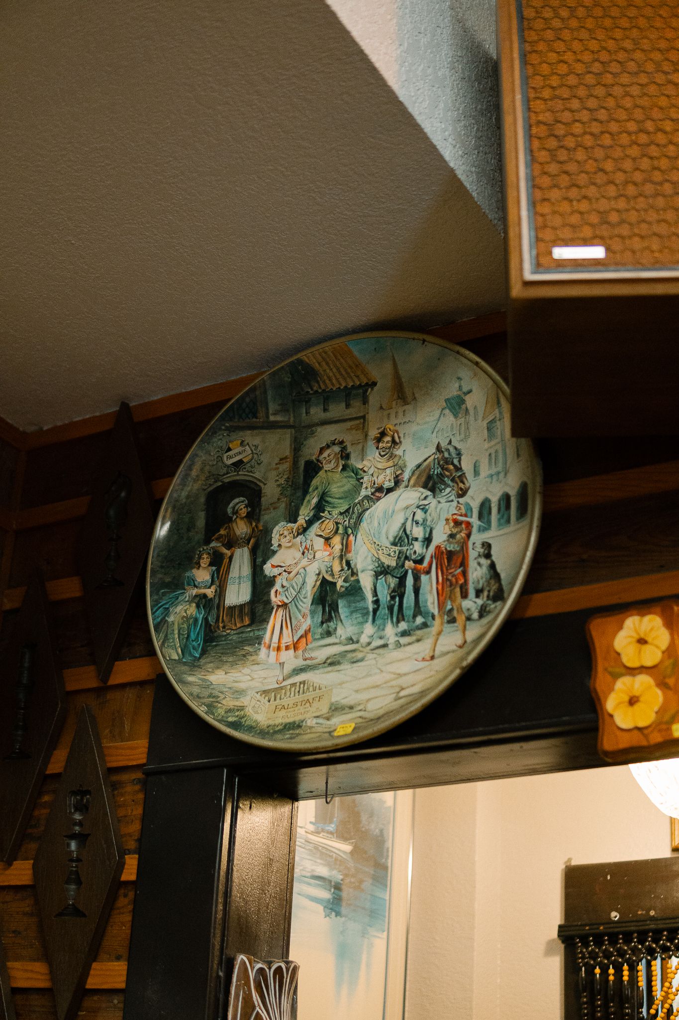Vintage decorative plates with folk art scenes displayed on a dark wooden shelf in dim lighting.