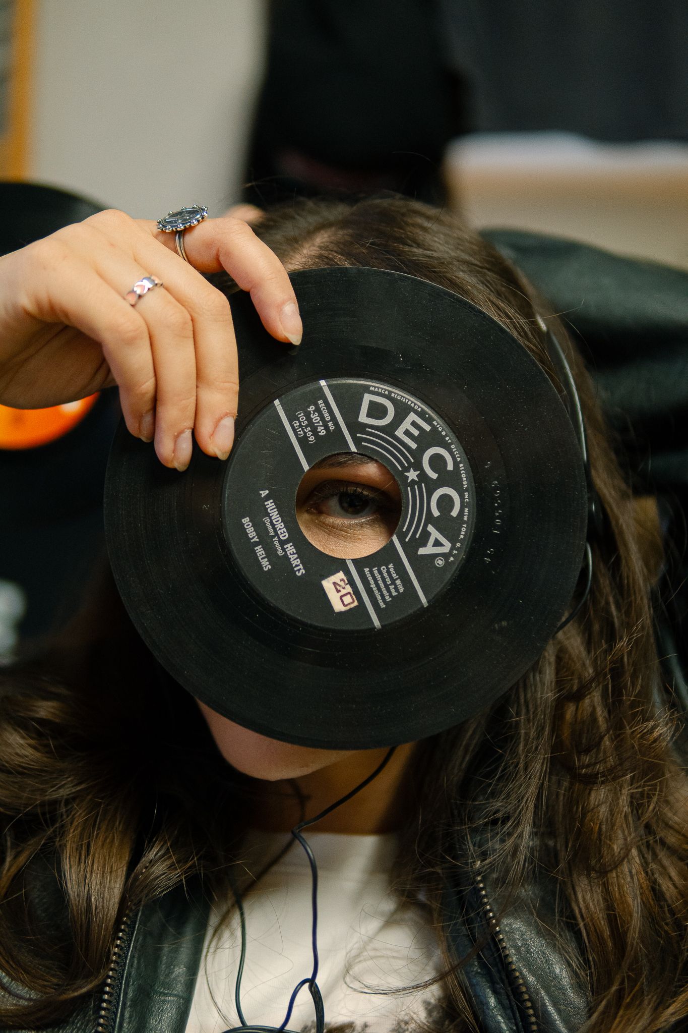 A series of four photos showing someone holding up a vinyl record in front of their face like a mask.