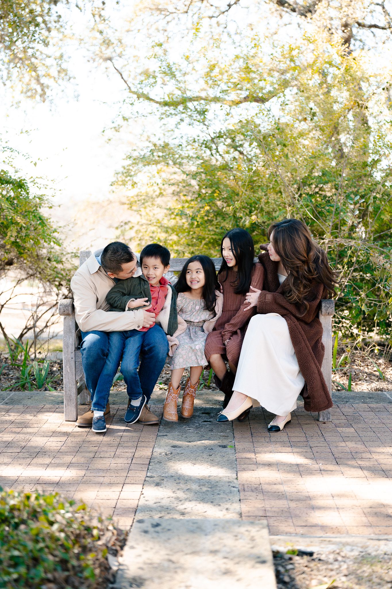 A group sits casually on stone steps in a garden setting during a sunny afternoon photo session.