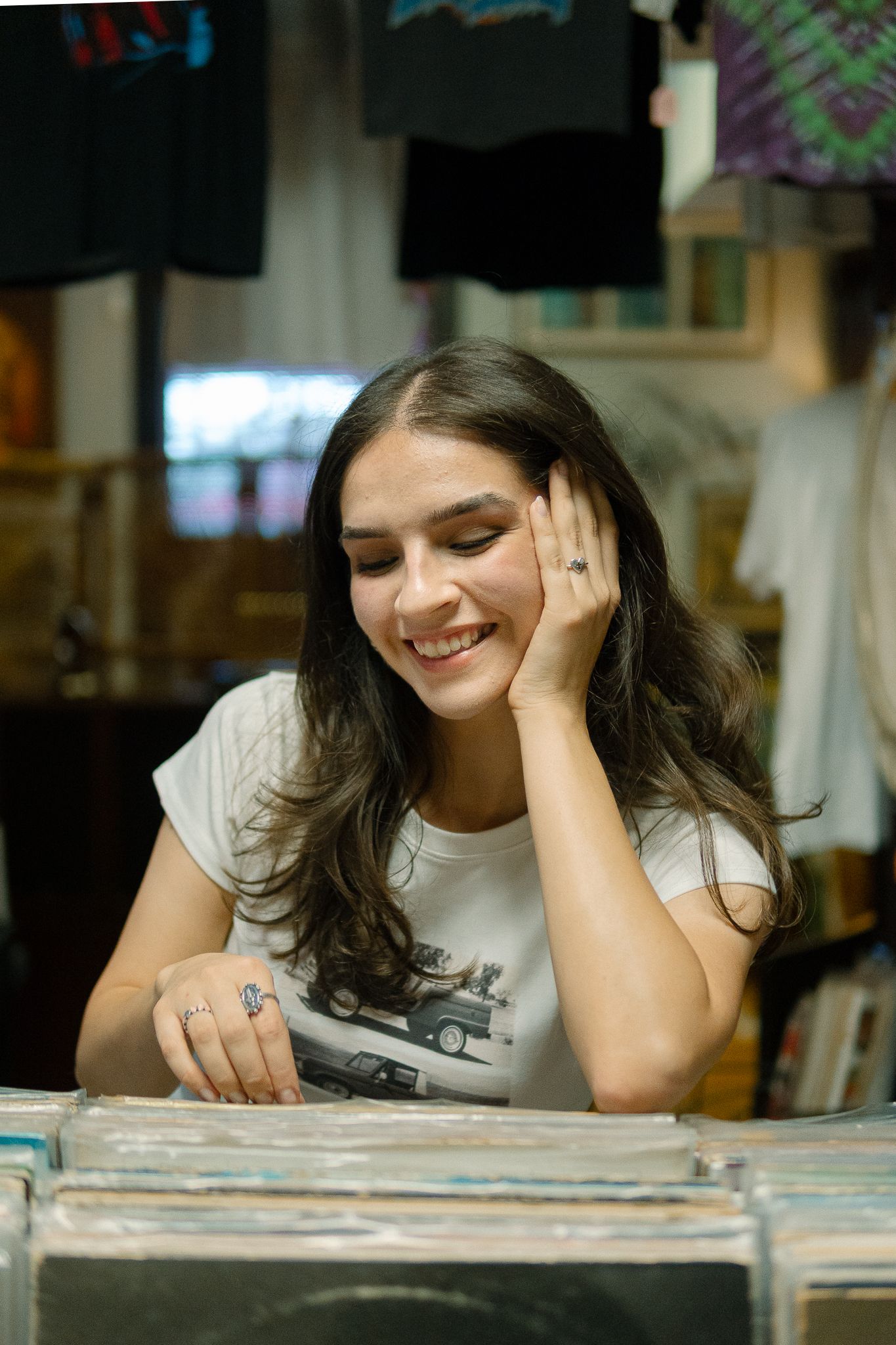 A person in a white t-shirt lies on their side browsing through vinyl records in a record store.