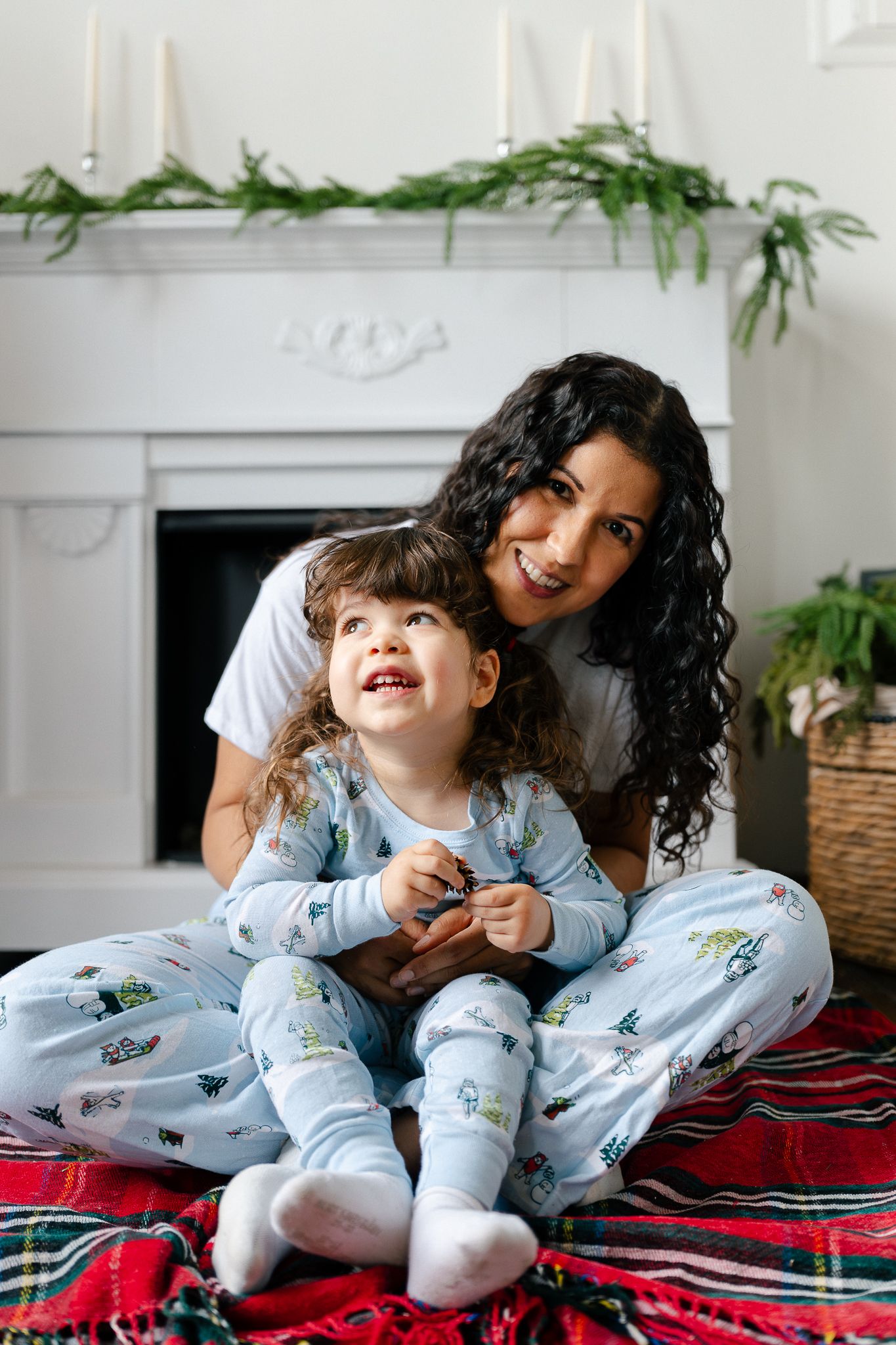 Playful moments captured on a red plaid blanket showing joyful interaction in matching light blue pajamas.