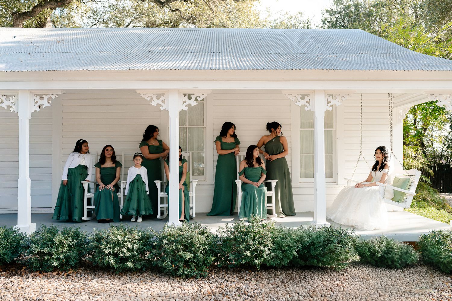 People gather on a white porch with green chairs and lush landscaping in a series of connected outdoor scenes.