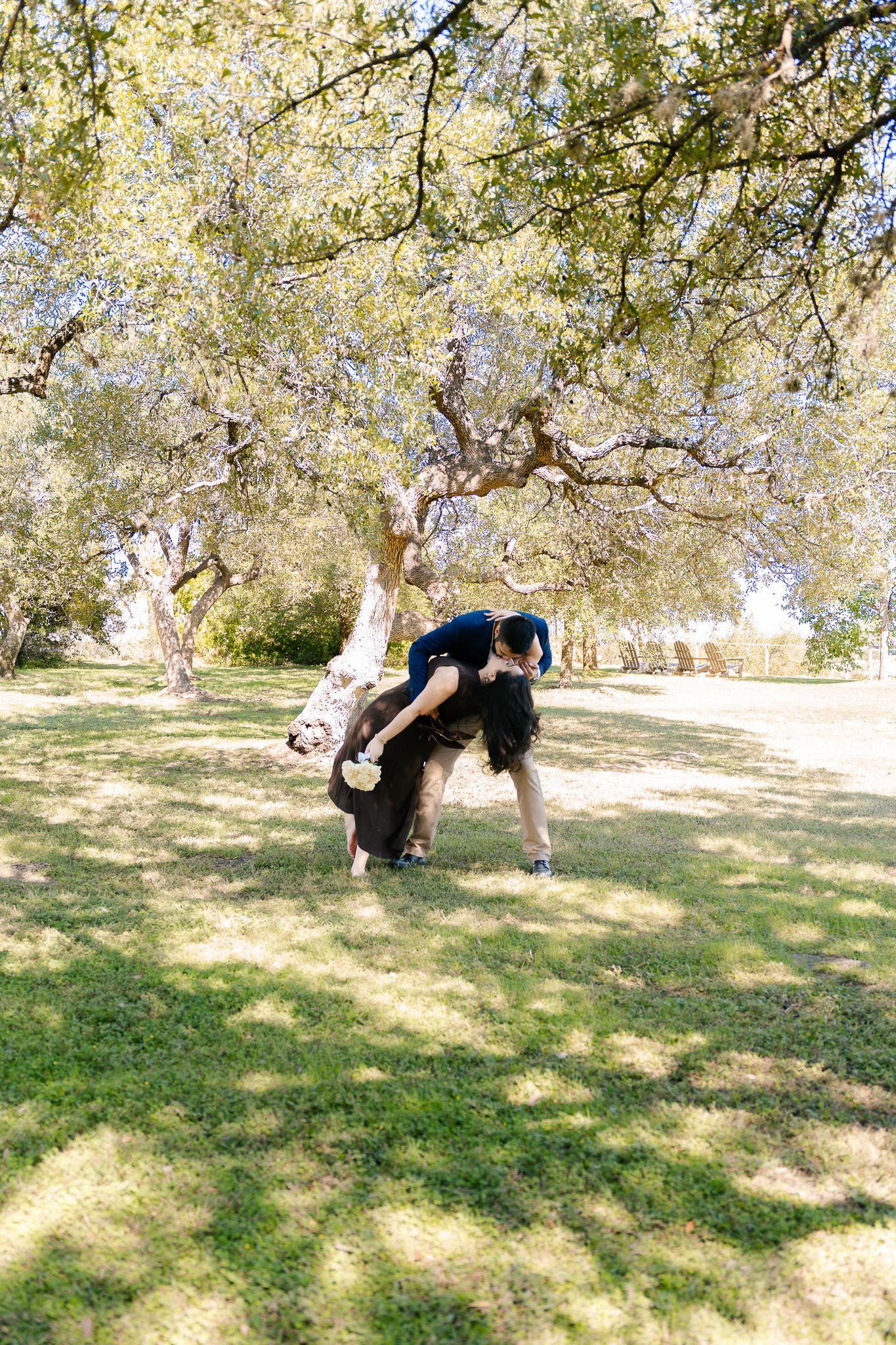 A sequence of backflips being performed on grass under trees in a park setting.