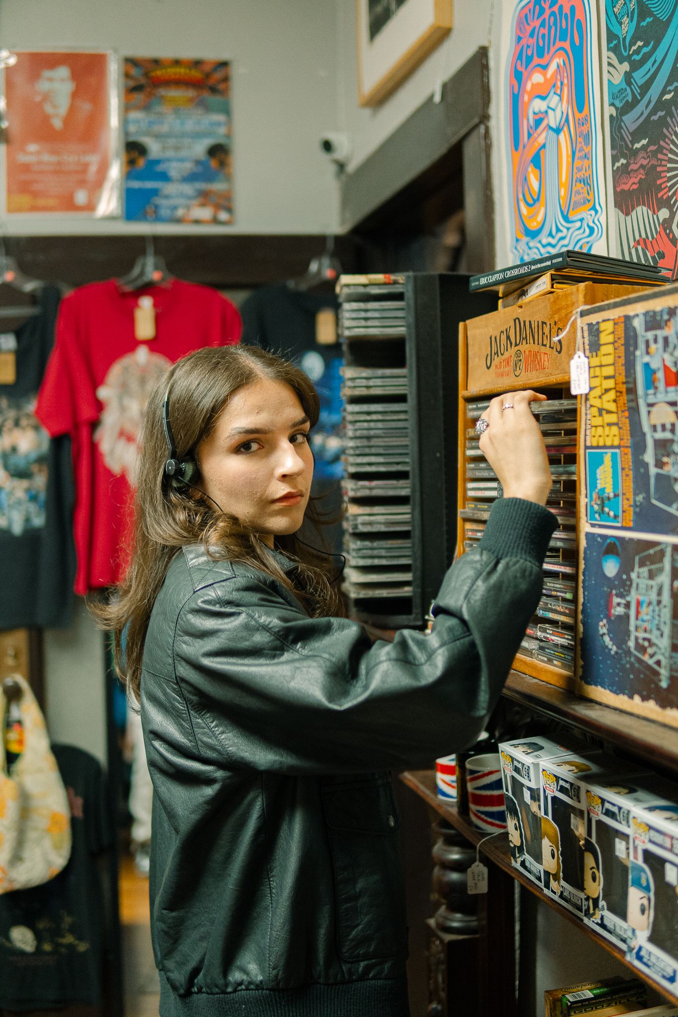 Person in black jacket browsing through vinyl records at a music store with colorful album covers on display.