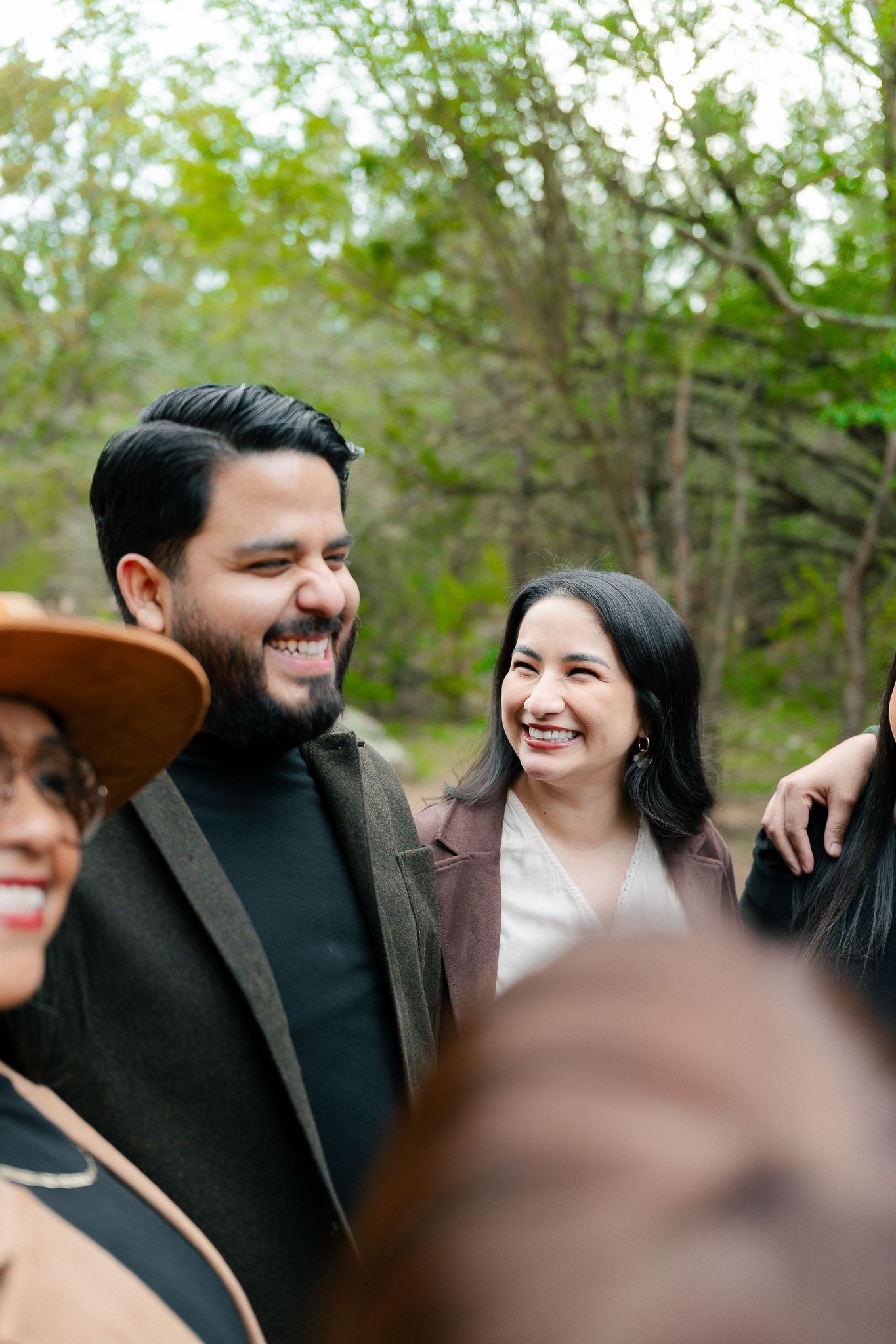 A couple shares joyful laughter together during an outdoor photo session in a natural setting.