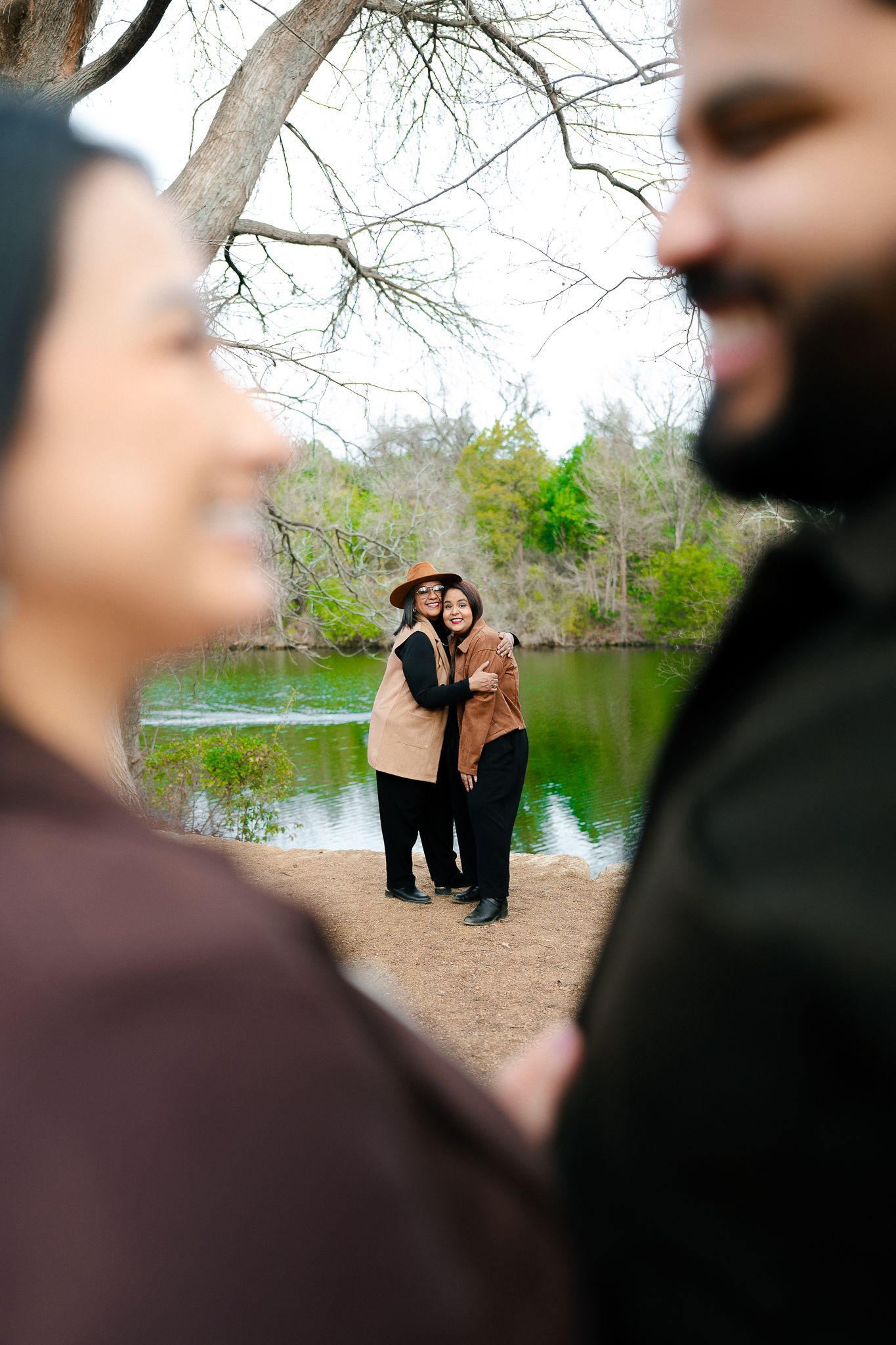 Romantic couple photoshoot sequence by a lake with bare trees and natural scenery in the background.