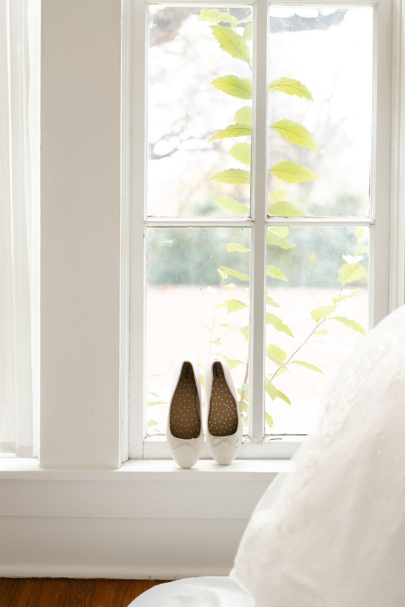 White curtains billow softly by a bright window with decorative pear-shaped vases on the sill.