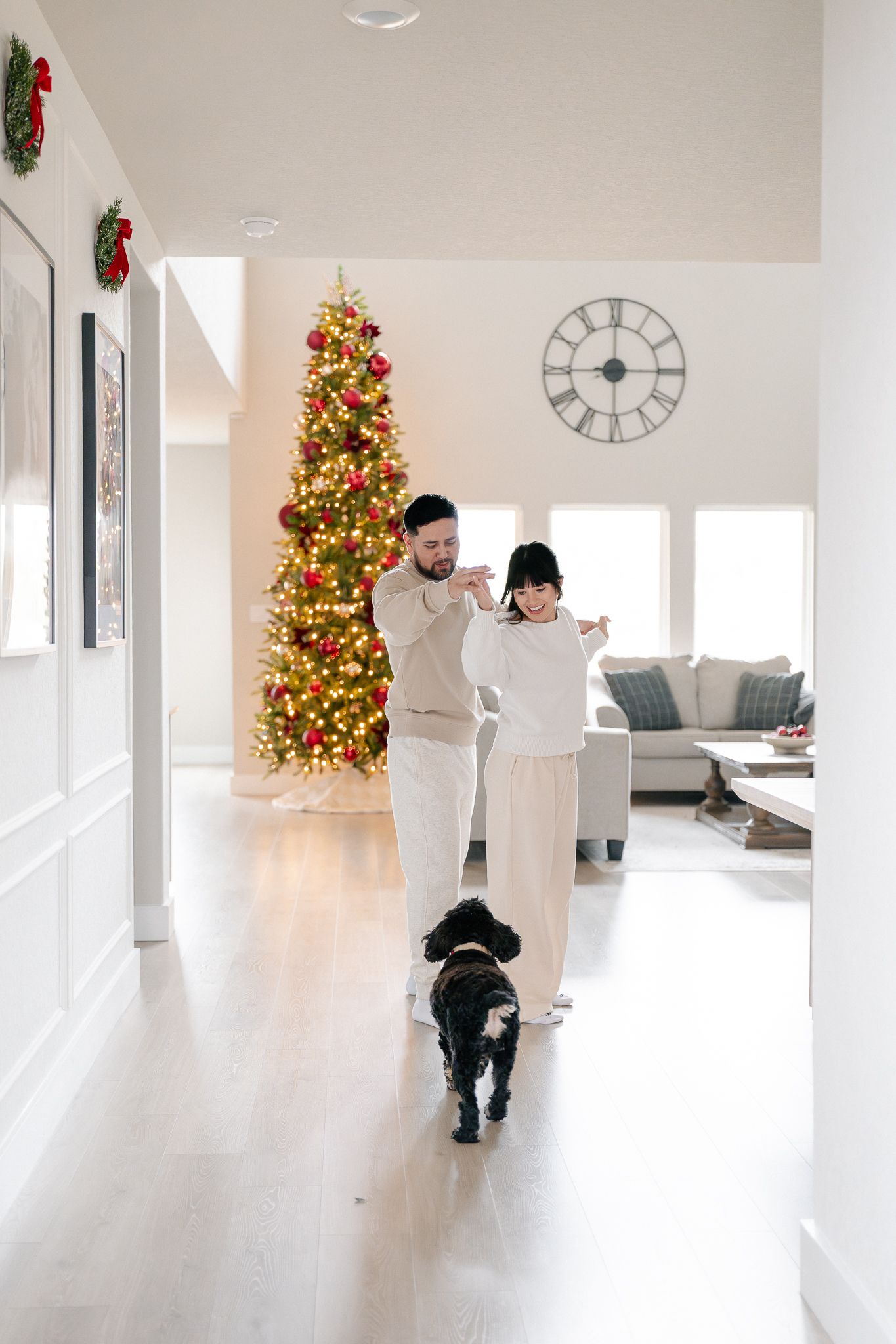 A bright white interior room decorated for Christmas with a lit tree and holiday garlands visible in multiple views.