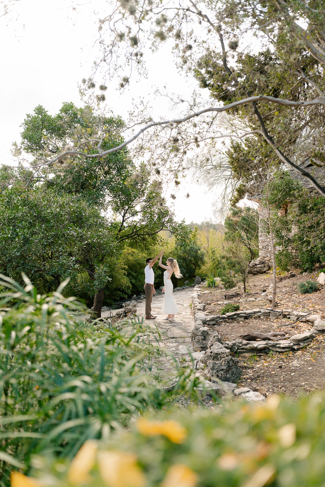 A scenic garden pathway winding through lush greenery and rock formations in a natural outdoor setting.