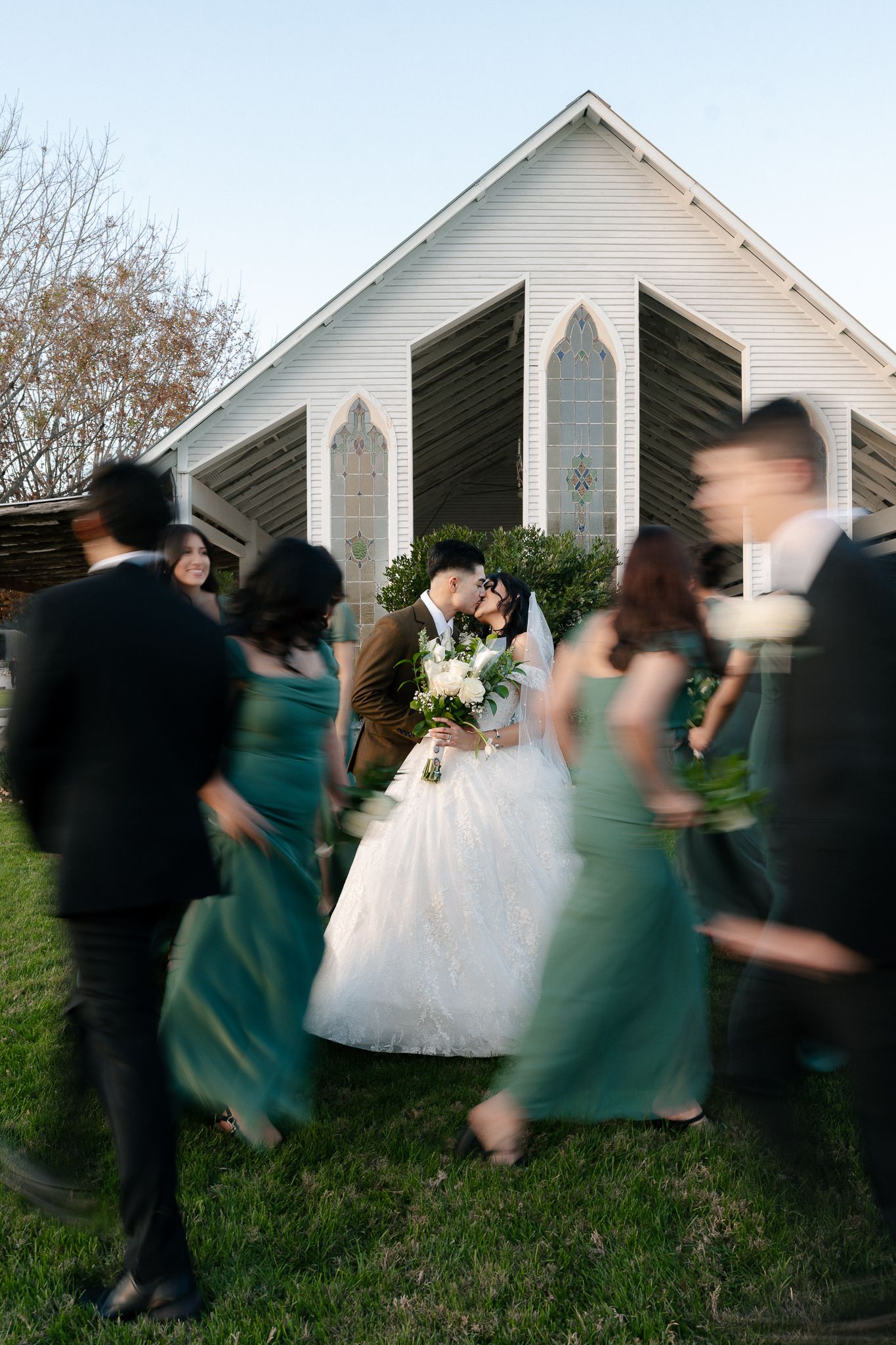 Motion blur captures a wedding party in teal dresses moving across a white church lawn in a sequence of images.