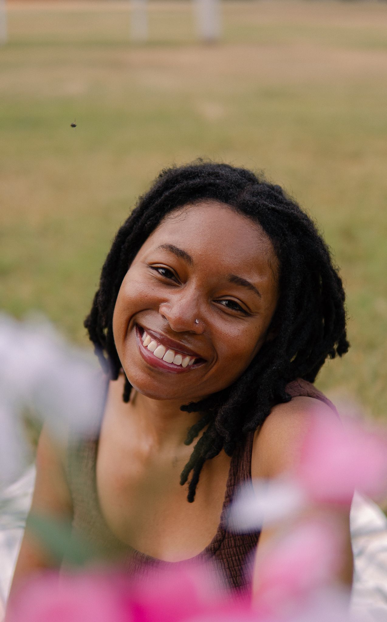 A joyful expression captured in a series of photos with pink flowers blurred in the foreground.
