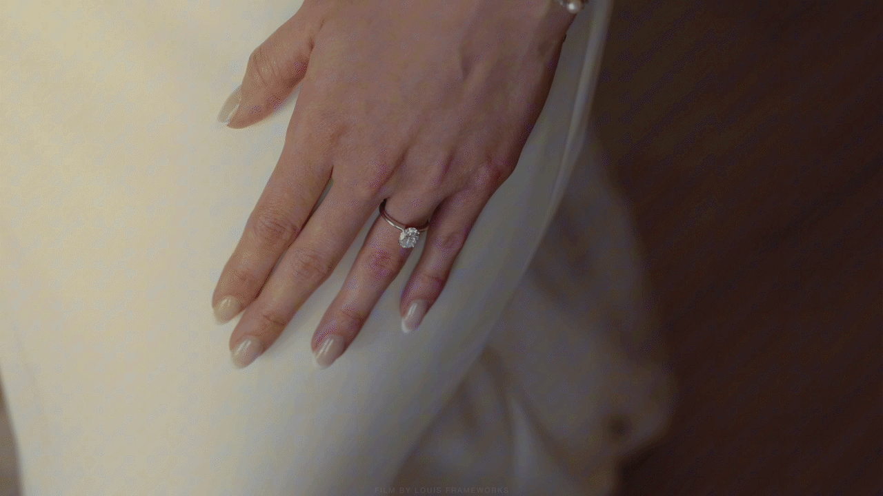 Close-up of a woman's hand wearing a diamond solitaire engagement ring on her ring finger.