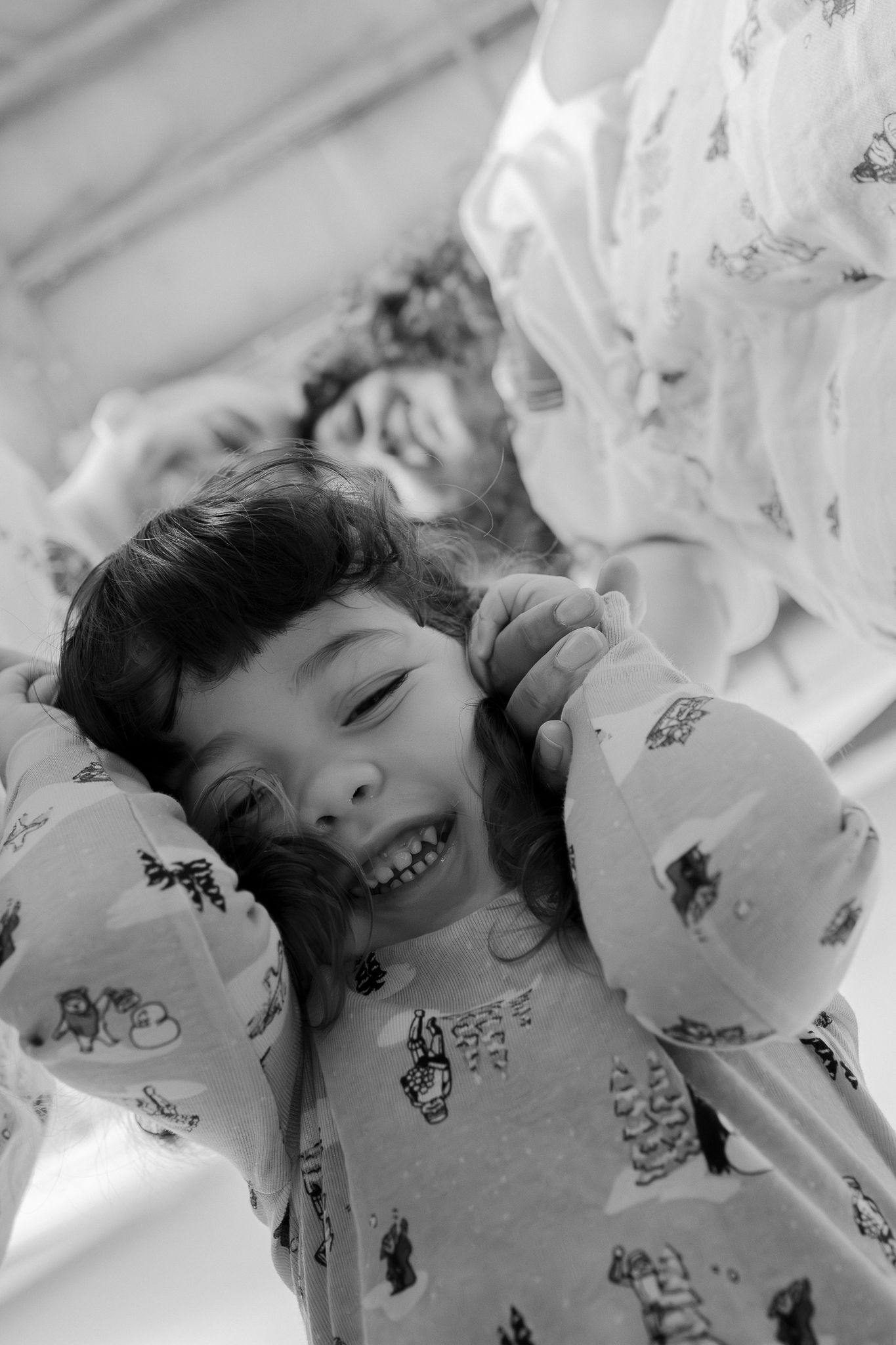 A black and white photo series shows a child lying down with patterned fabric or sheets, captured from different angles.