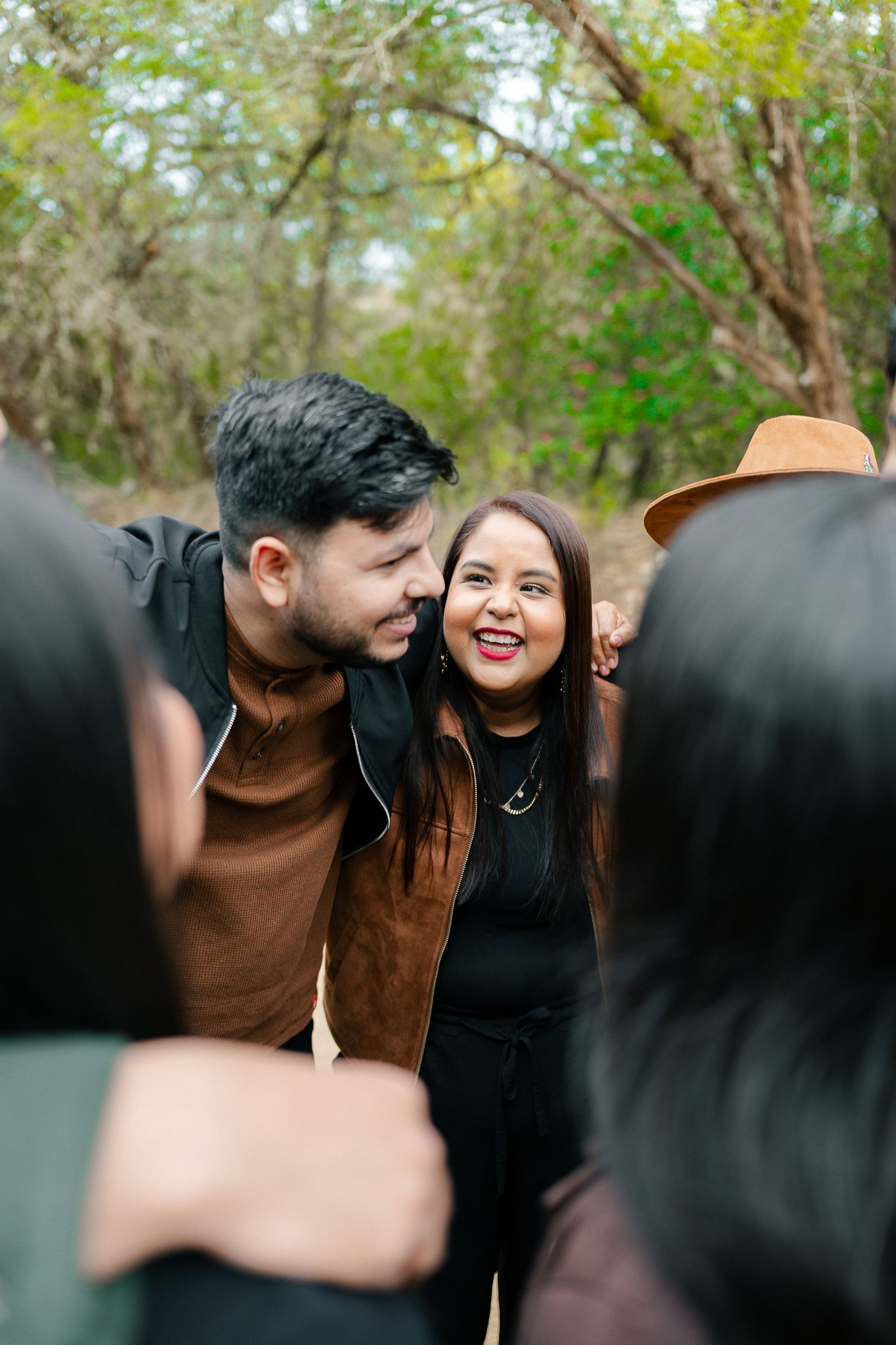 A romantic couple sharing tender moments together in a natural outdoor setting with green foliage in the background.