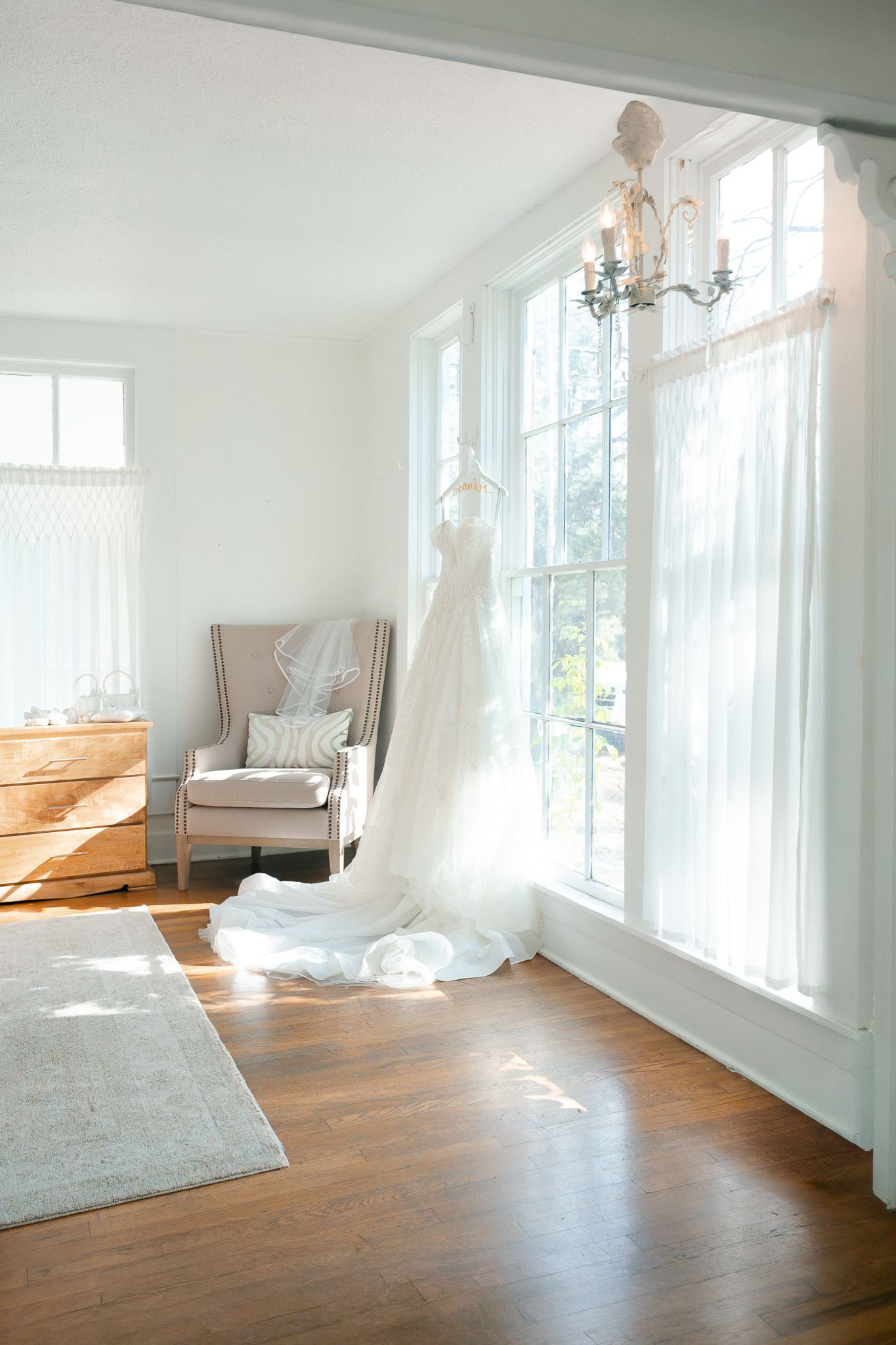 Bright sunlit room with hardwood floors, white walls, and large windows showcasing elegant minimalist interior design.
